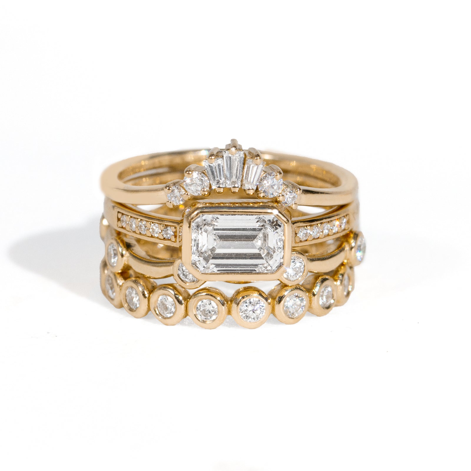 Stack of gold rings with diamond accents on a white background