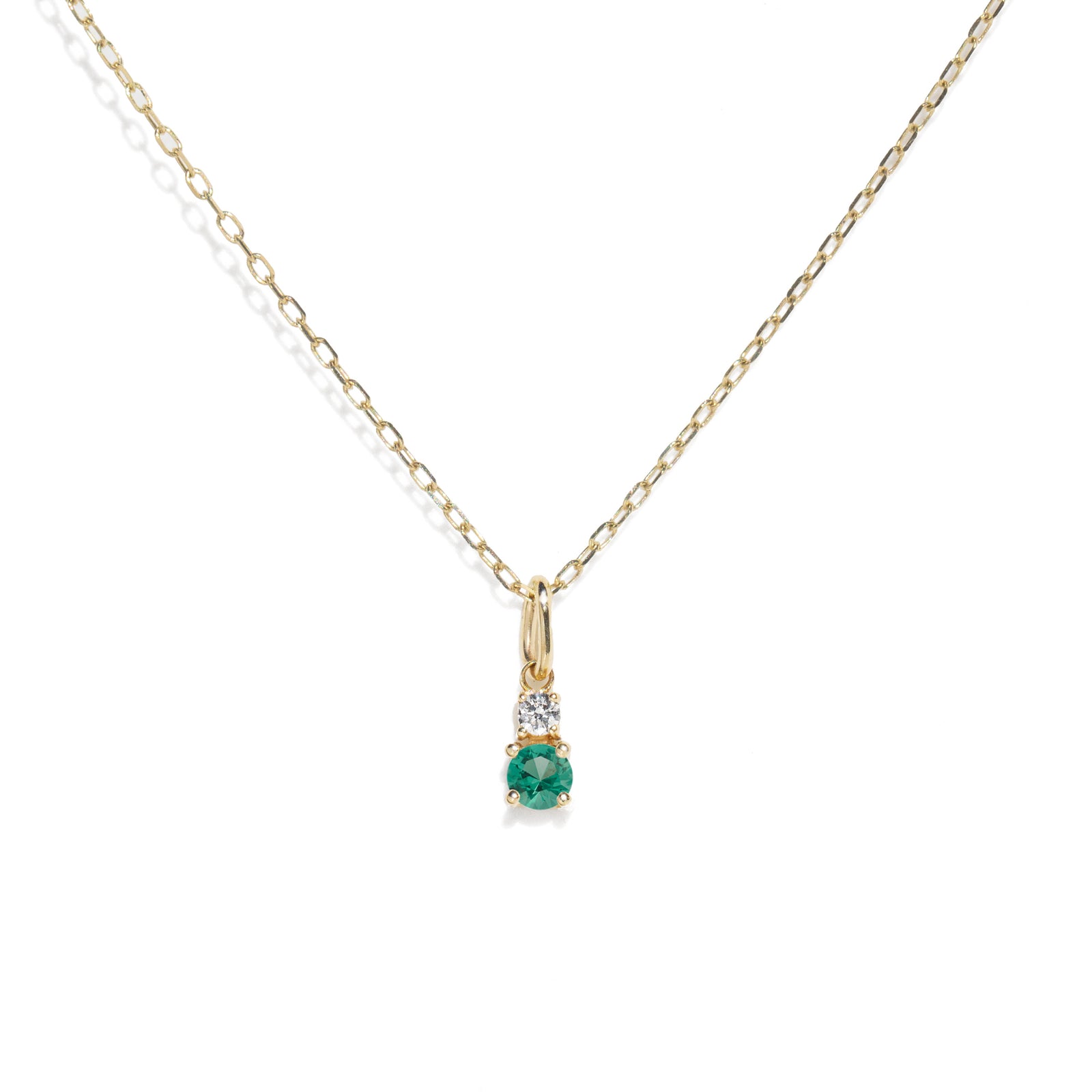 Gold necklace with a green gemstone pendant on a white background