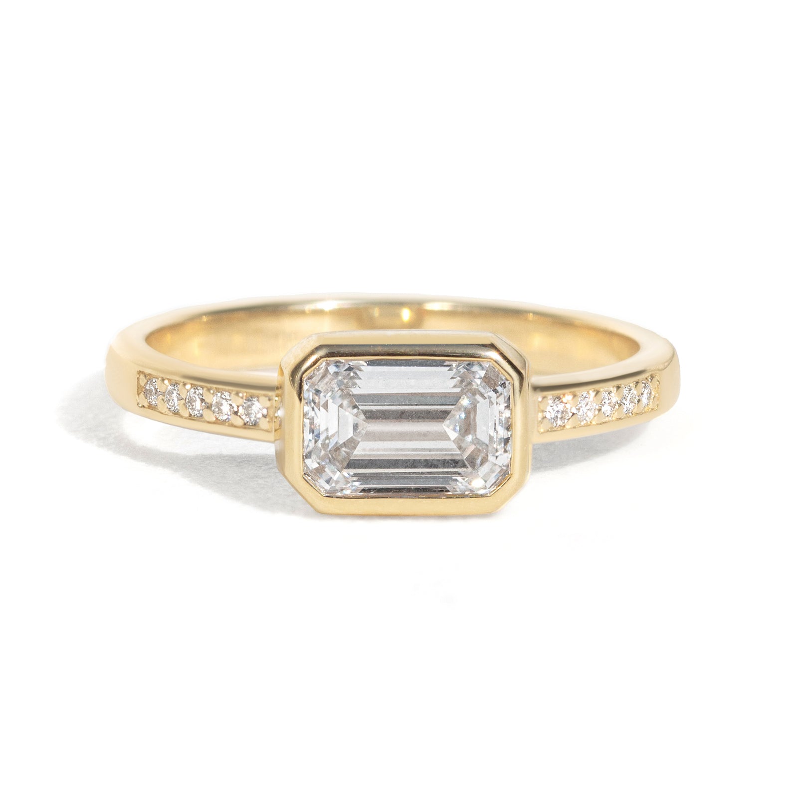 The Zoey Ring features a 1-carat emerald-cut diamond or moissanite in an east-west setting. The smooth bezel setting ensures everyday wear, while delicate accent diamonds add sparkle from every angle