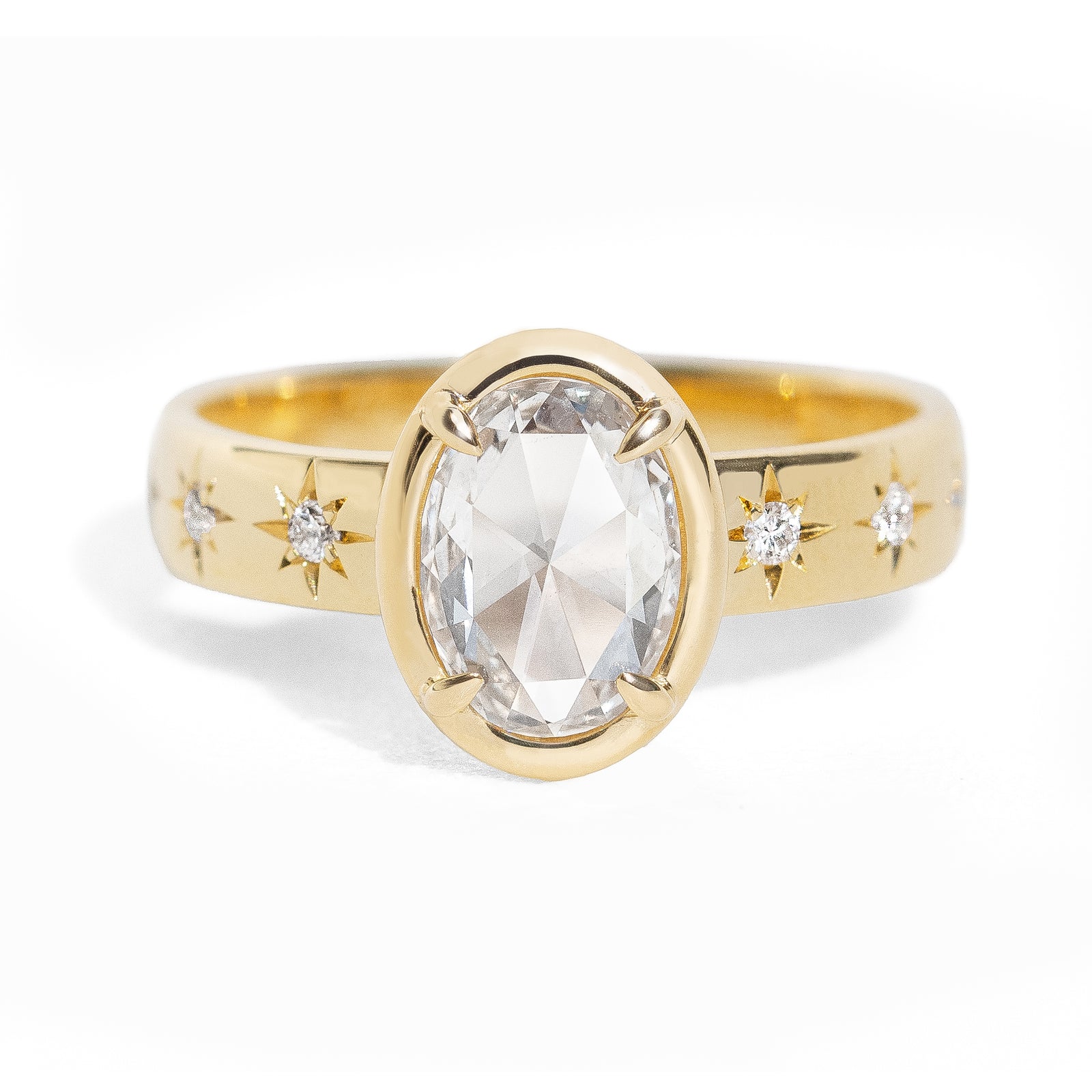 Gold ring with a large oval rose cut diamond and smaller diamonds on the band against a white background