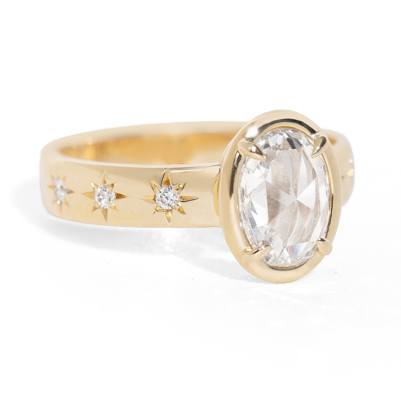 Gold ring with a large oval rose cut diamond and smaller diamonds on the band against a white background
