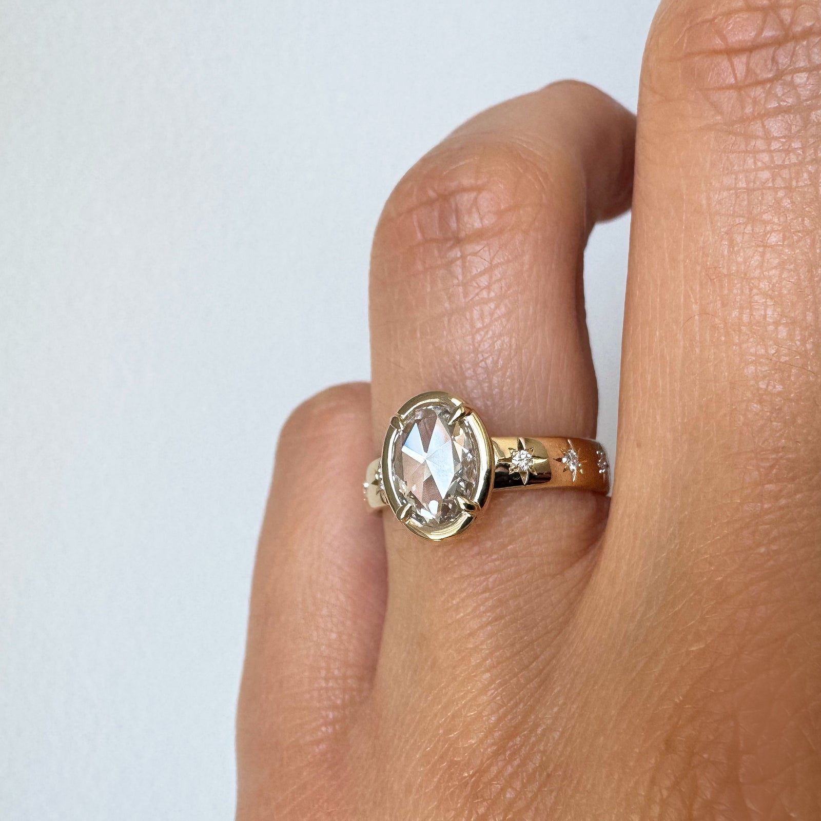 Gold ring with a diamond on a finger against a white background