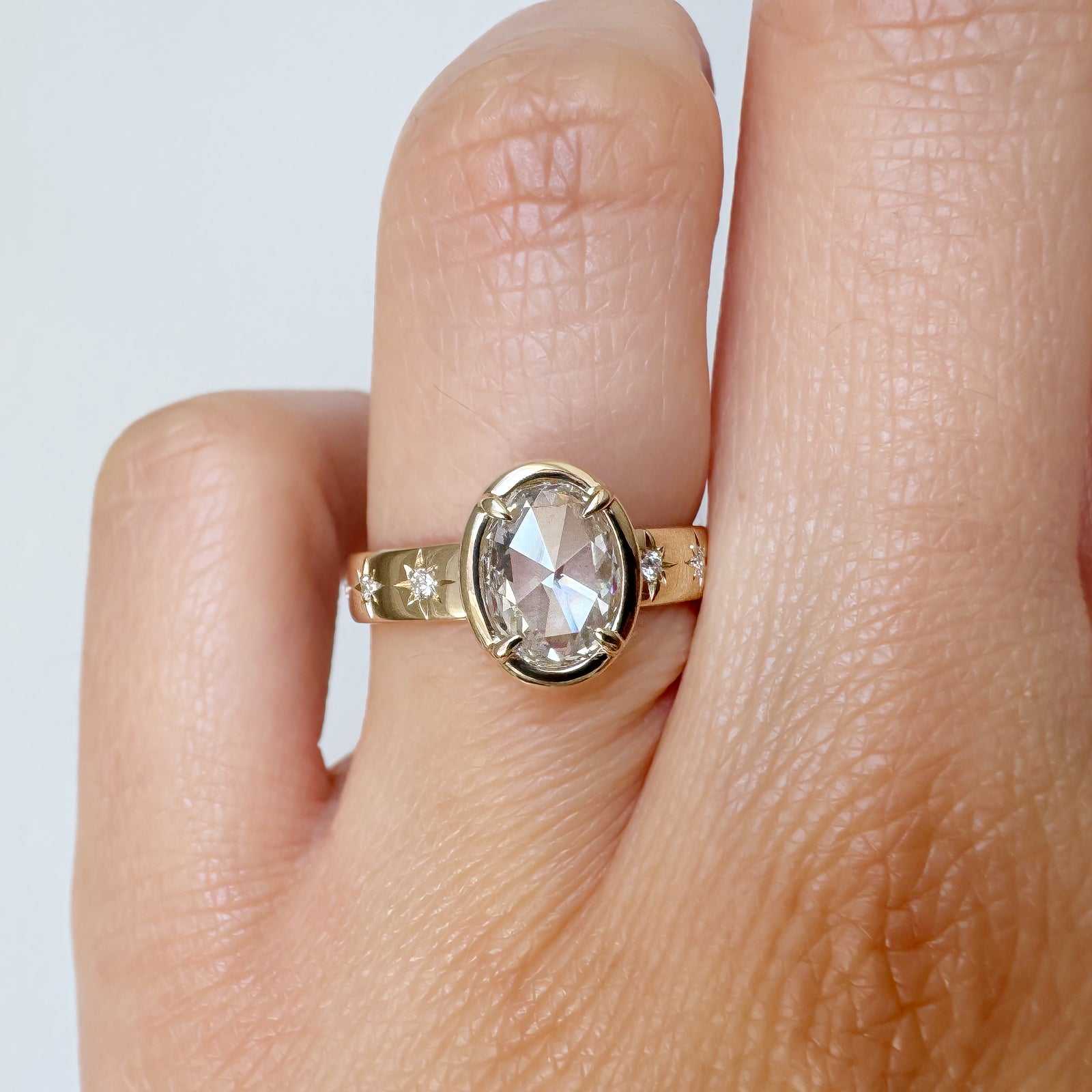 Gold ring with a large diamond on a finger against a white background