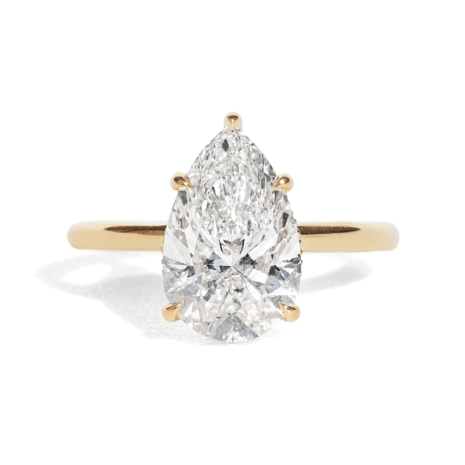 Gold ring with a pear-shaped diamond on a white background