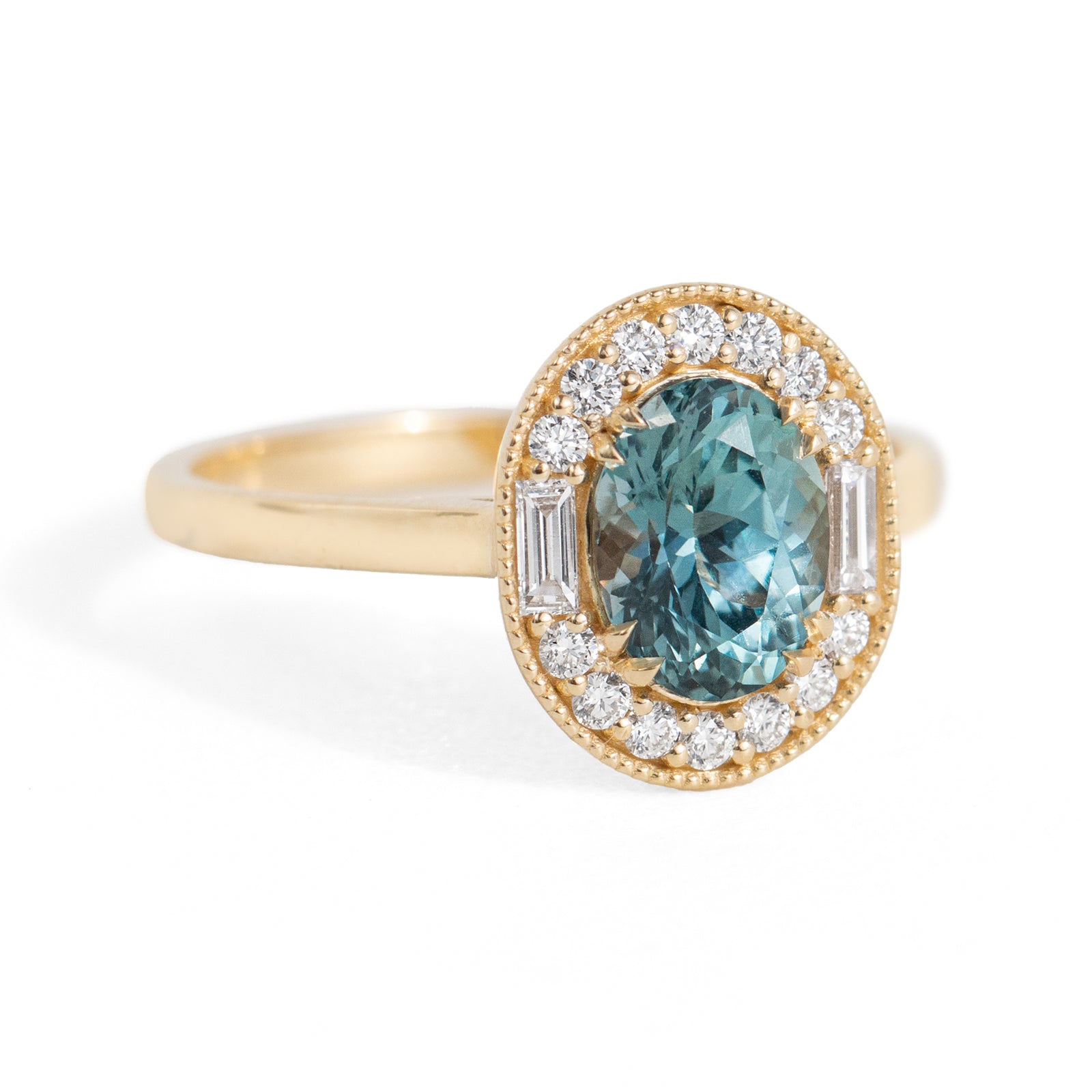 Gold ring with a teal gemstone and diamond accents on a white background