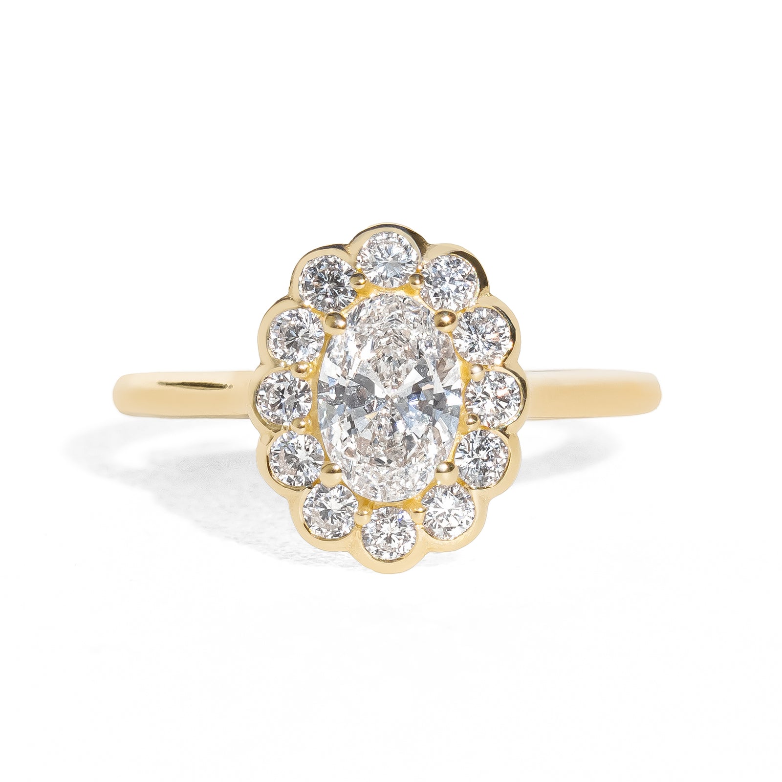Gold ring with an oval diamond framed by small round halo diamonds on a white background