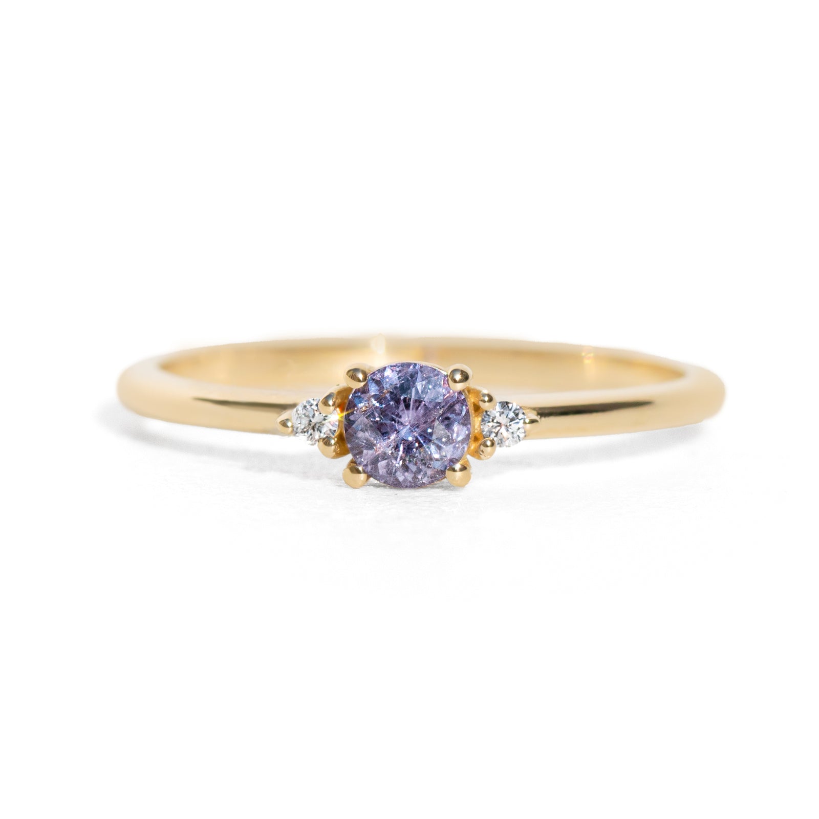 Gold ring with a purple sapphire on a white background