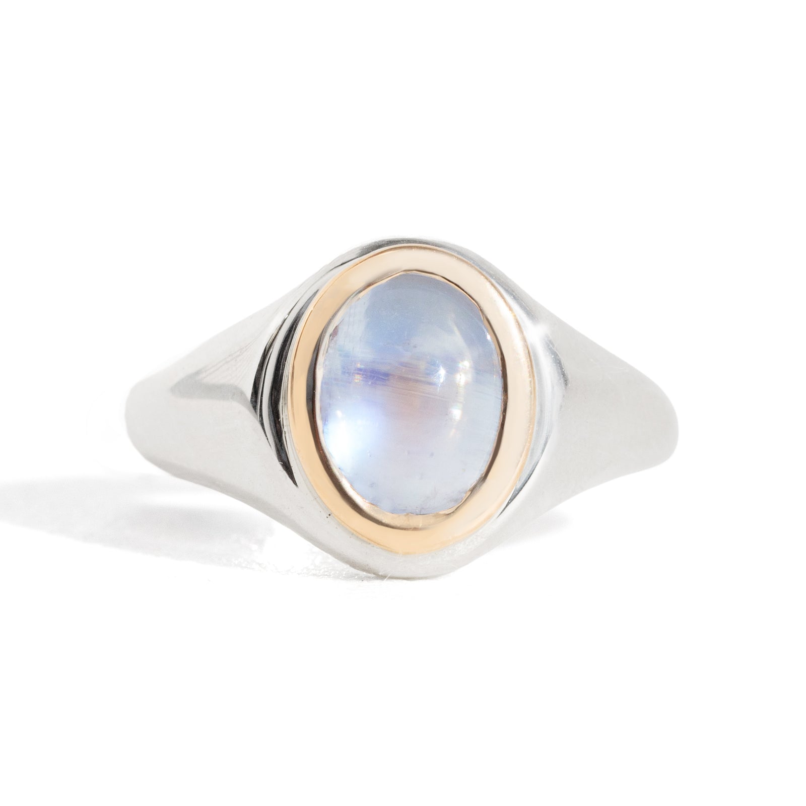 Ring with a blue moonstone and gold bezel setting on a silver band against a white background