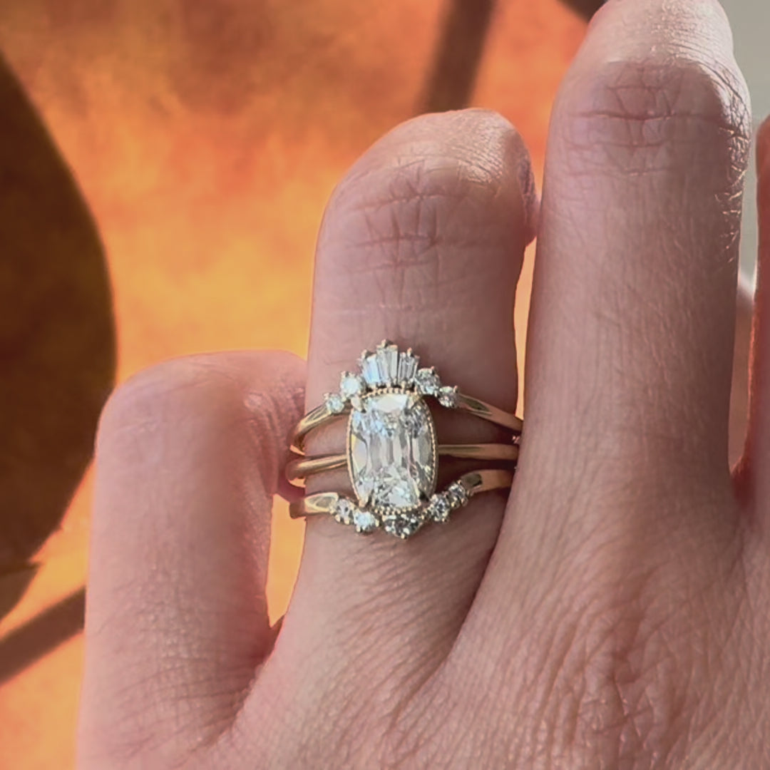 three diamond rings stacked on a hand in a brown background.