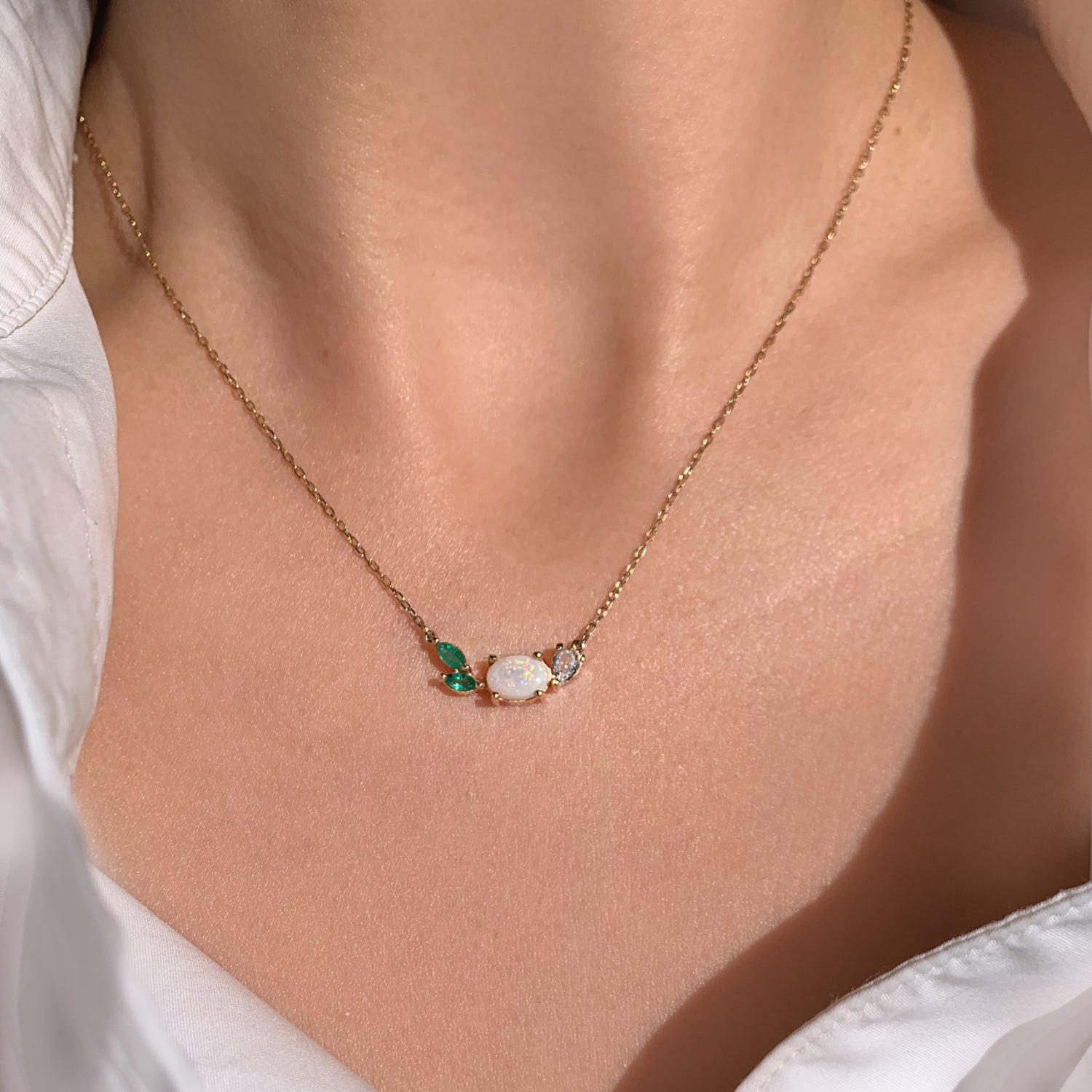 This beautiful, 14K gold-cast necklace is inspired by the tranquility of a lush evergreen. Adorned with a cluster of gorgeous gemstones, including an Australian opal and two emeralds, it's finished with a sparkly pear-cut lab diamond.