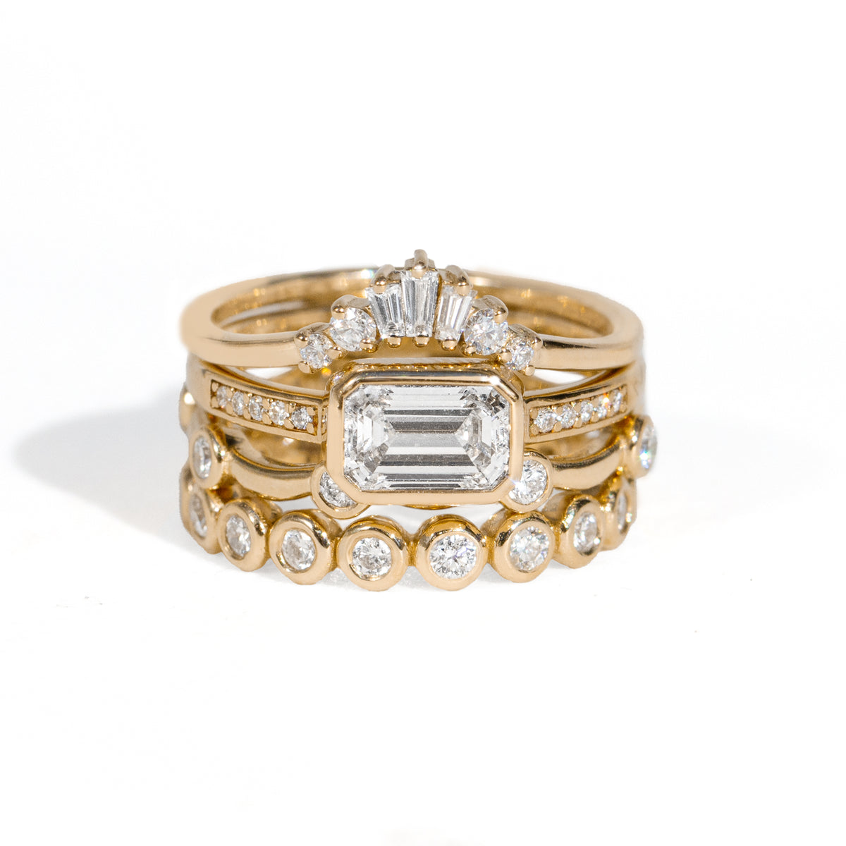 Stack of gold rings with diamond accents on a white background