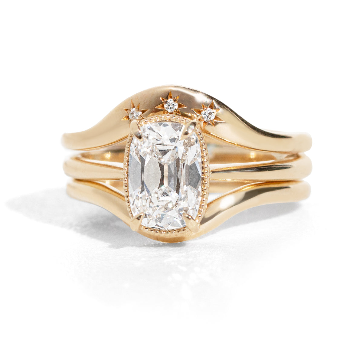 Old mine cut diamond ring stacked with contour wedding bands on a white background. 