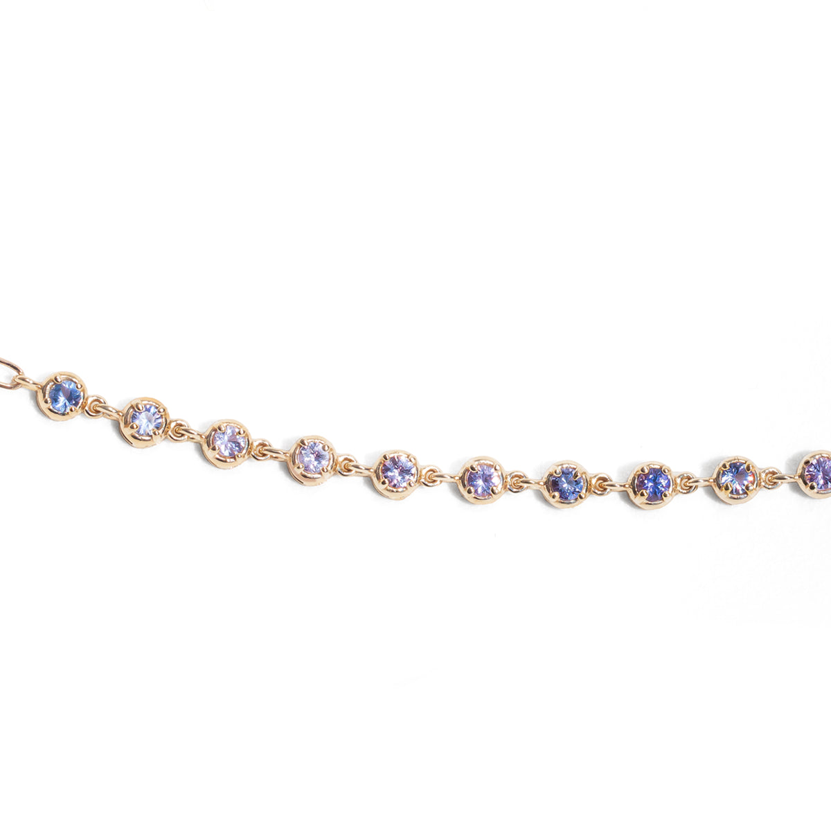 Gold bracelet with blue gemstones on a white background