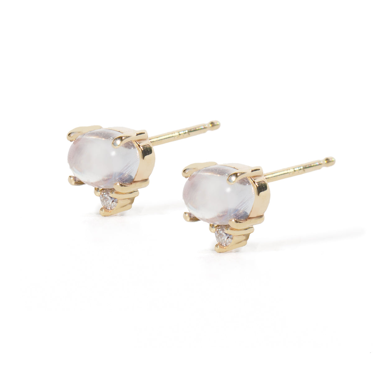A pair of gold stud earrings featuring oval milky white moonstone cabochons and small clear accent stones, set in polished yellow gold prong settings on a white background.