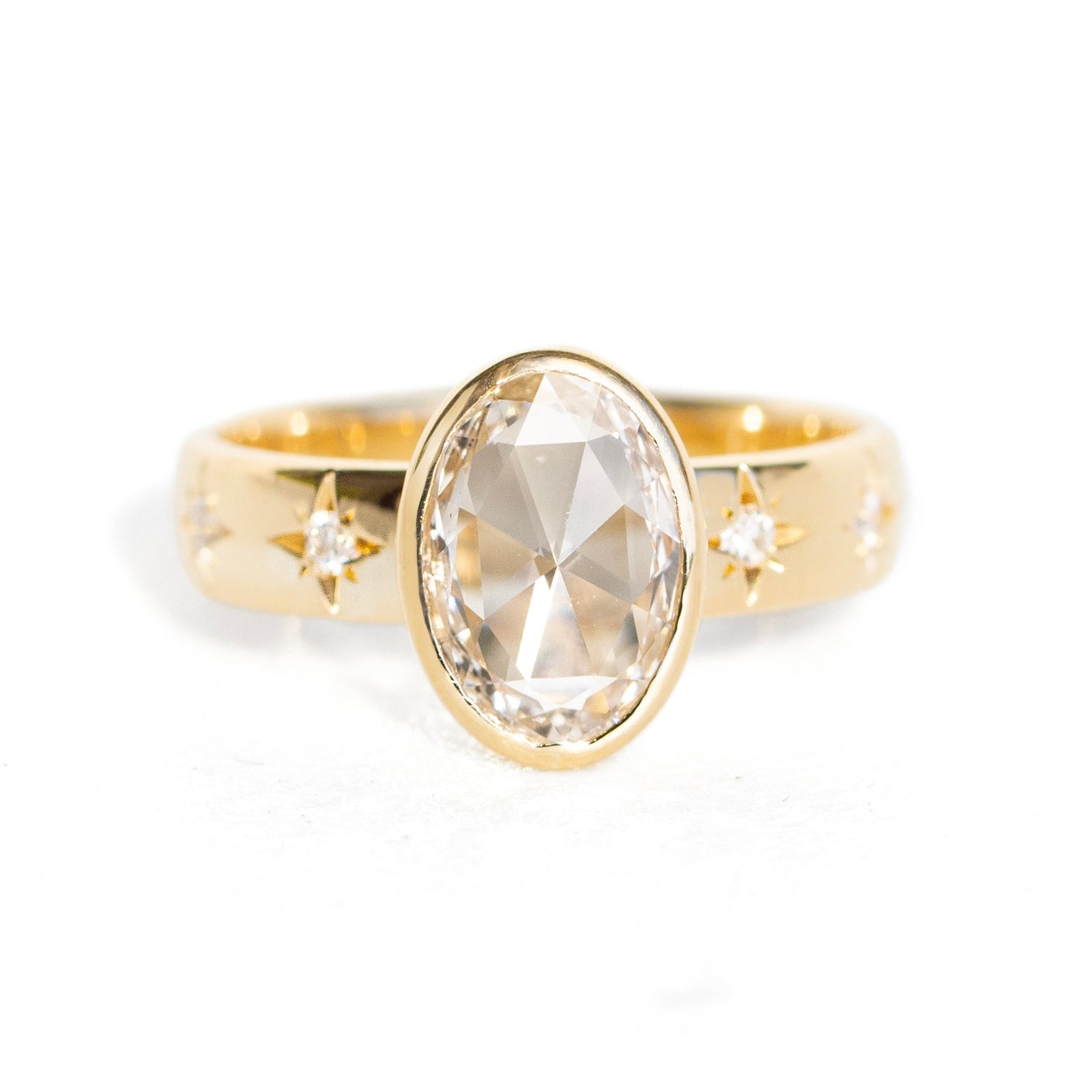 A gold ring with a marquise-cut clear gemstone and small star-shaped accents on the band, photographed against a solid white background.