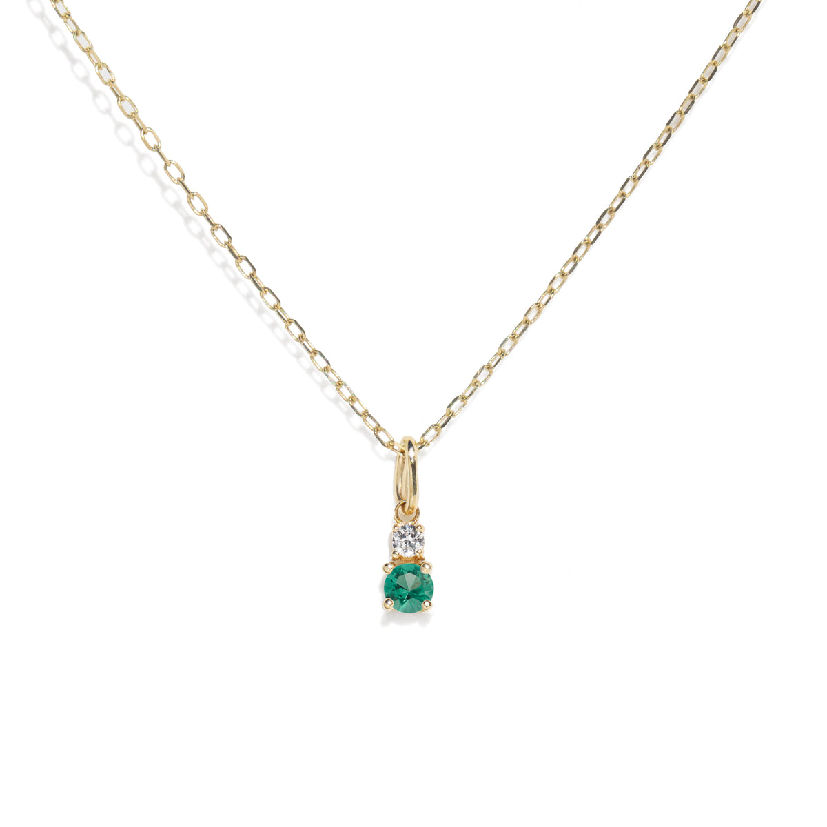 Gold necklace with a green gemstone pendant on a white background