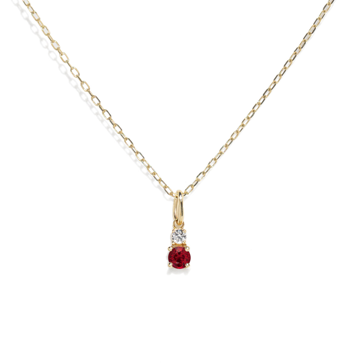 Gold necklace with a red gemstone pendant on a white background