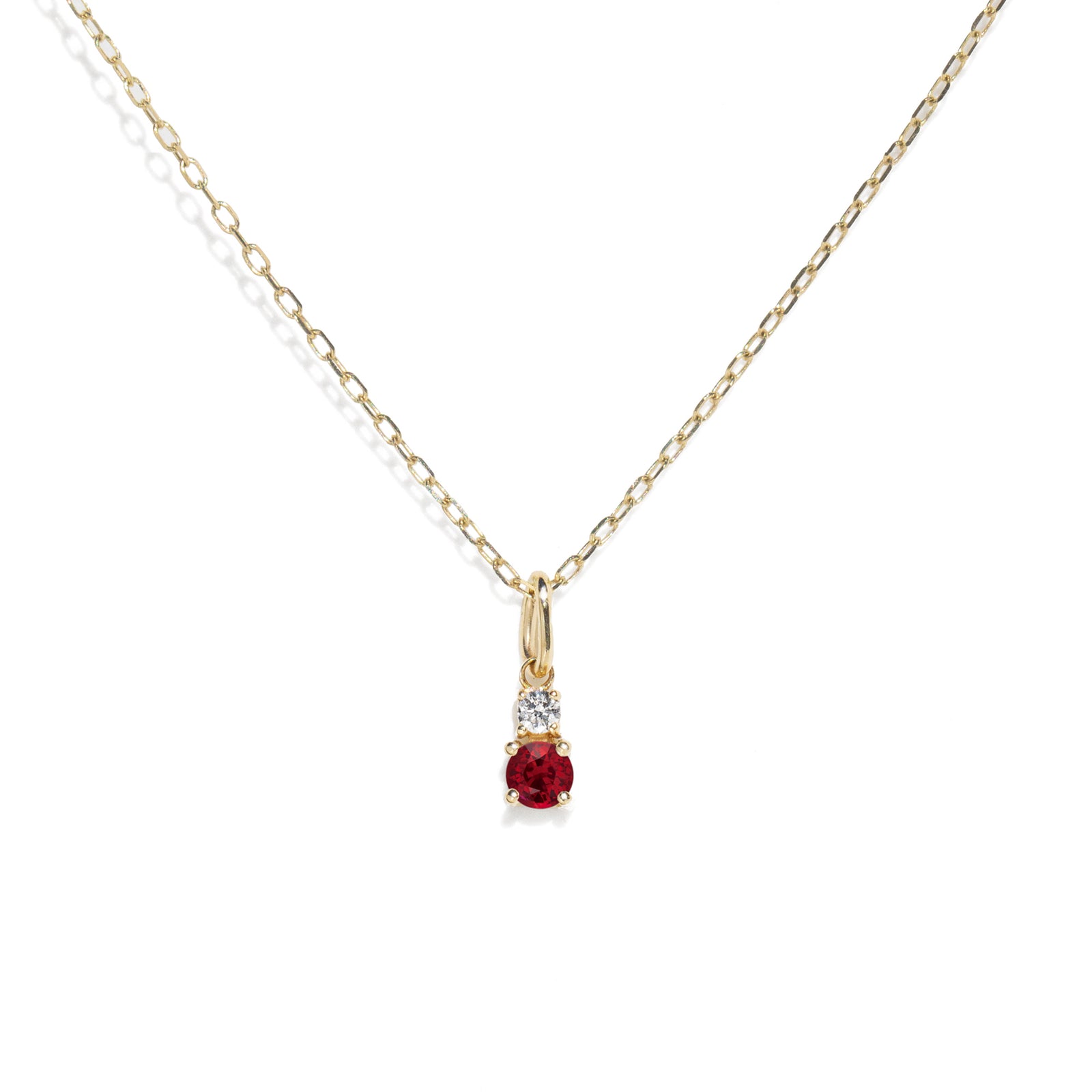 Gold necklace with a red gemstone pendant on a white background
