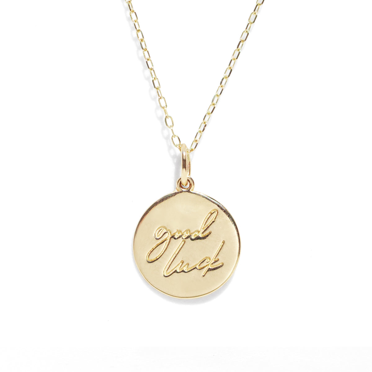 Gold necklace with a round pendant engraved with 'good luck' on a white background