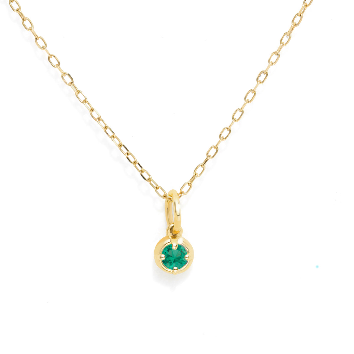 A delicate yellow gold chain necklace with a small bezel-set round green gemstone pendant, displayed on a clean white background.
