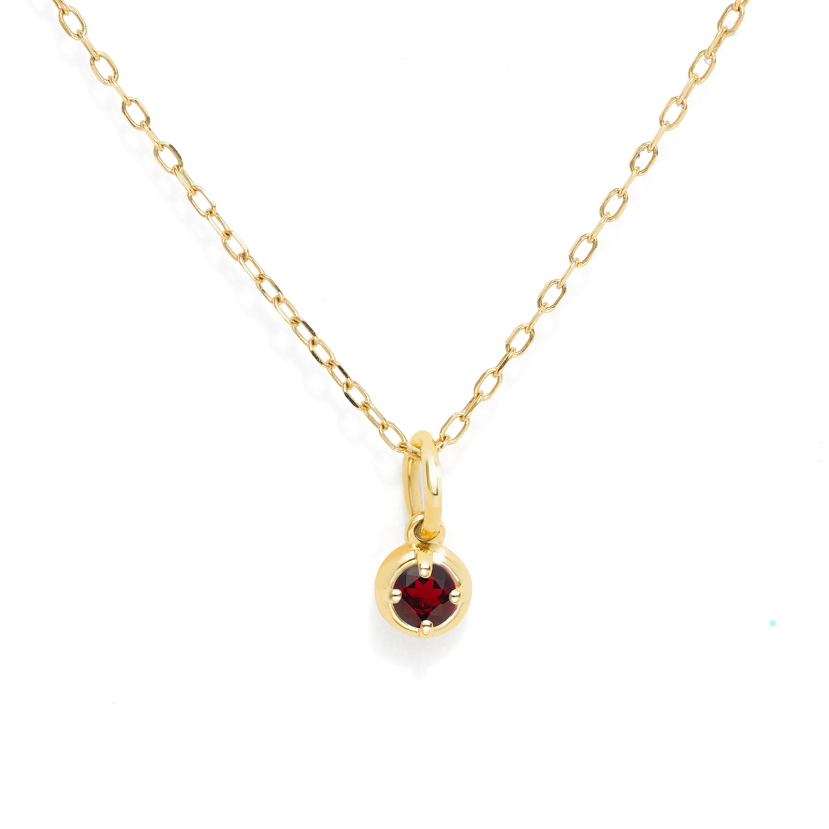 A gold chain necklace with a small circular gold pendant holding a round red gemstone, shown on a plain white background.