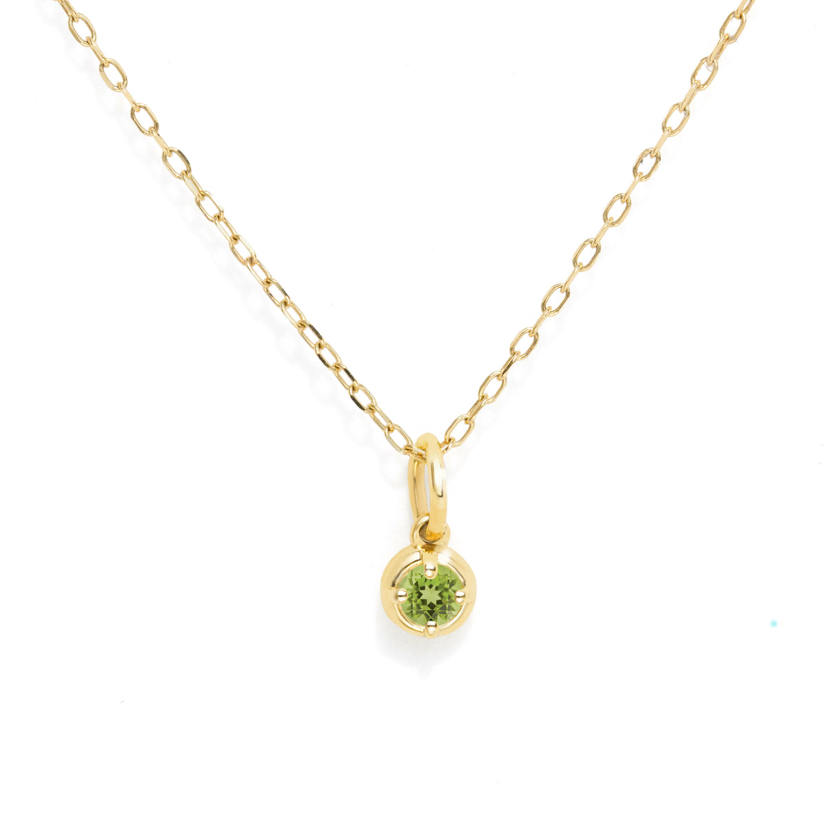 A delicate yellow gold chain necklace with a small oval pendant featuring a round-cut green gemstone, set against a plain white background.