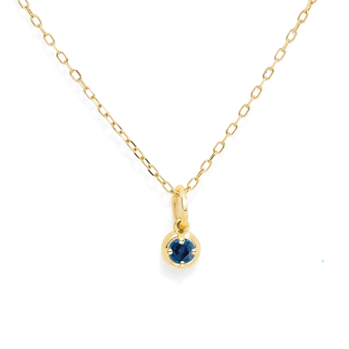 A delicate yellow gold chain necklace with a small bezel-set round blue gemstone pendant, shown against a plain white background.