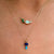 Two gold necklaces with opal pendants on a person's neck.
