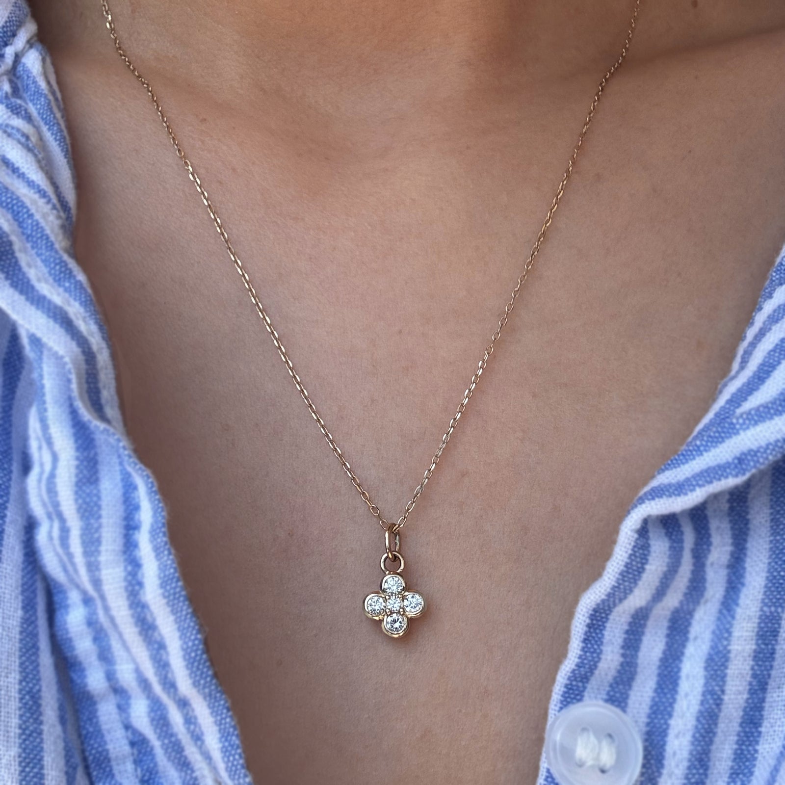 A diamond pendant necklace worn on a woman's neck