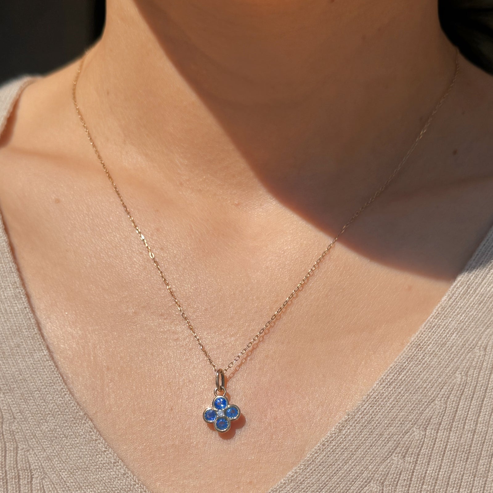 Necklace with a blue flower pendant worn by a person