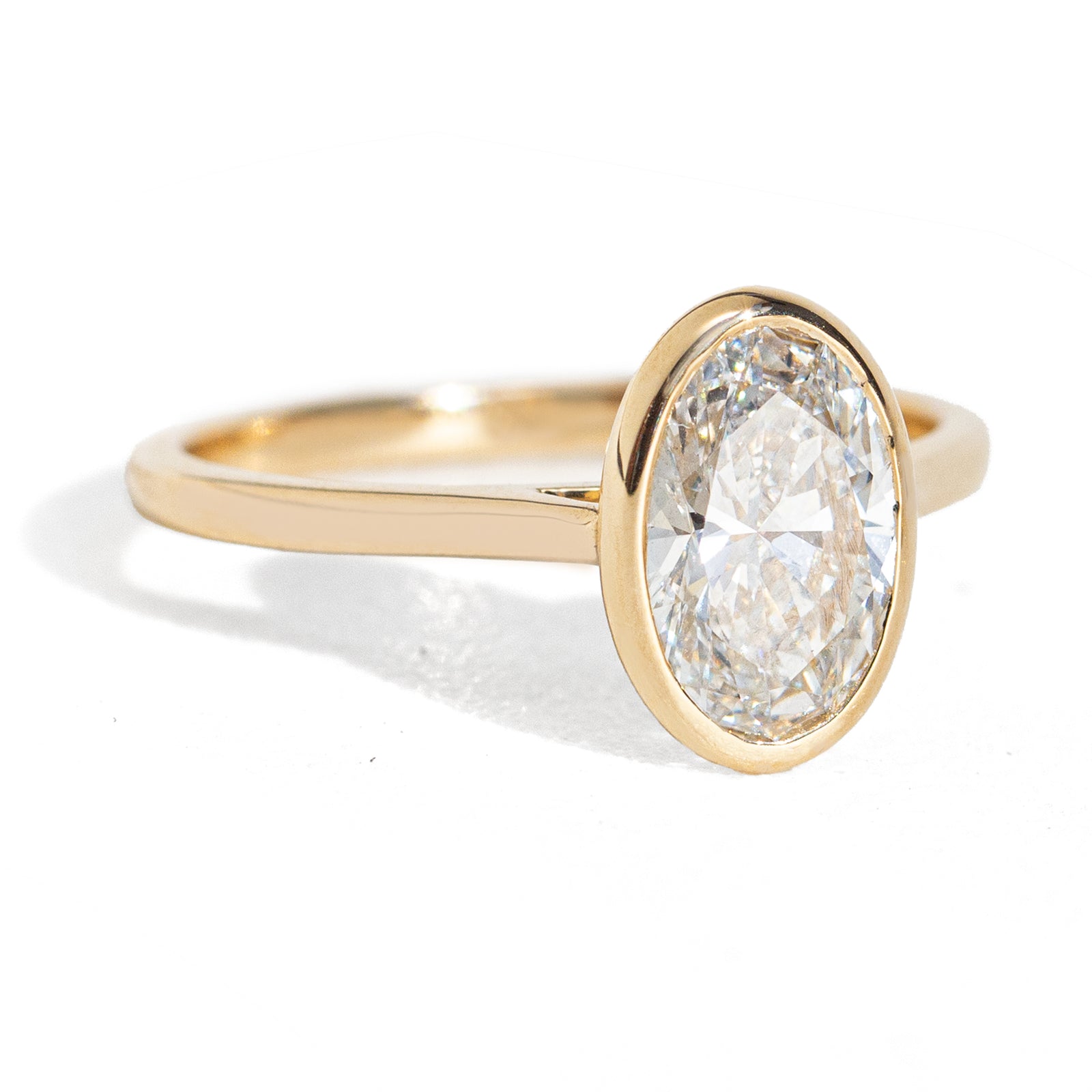 The Oval Diamond Classic Bezel Ring features timeless elegance with a IGI or GIA certified oval diamond set in our classic bezel setting. Completely snag-free, this ring ensures a clean, polished look. Its versatile design allows for easy stacking with any favorite band, making it a perfect addition to your collection for years to come. Shown in a 1.5ct size.