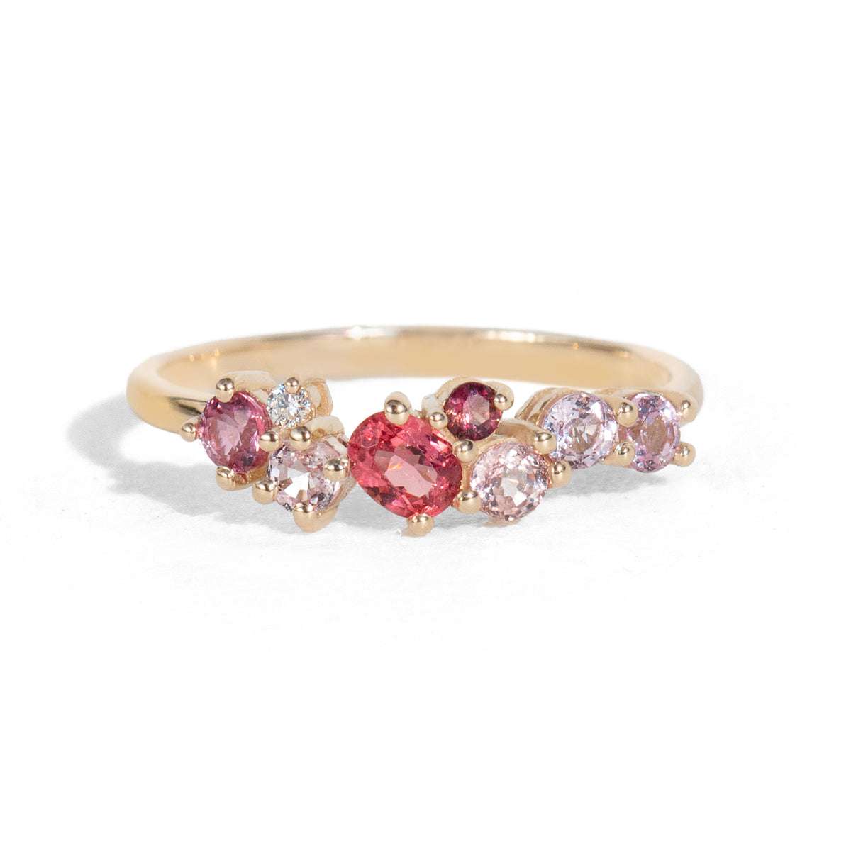 Gold ring with pink and red gemstones on a white background