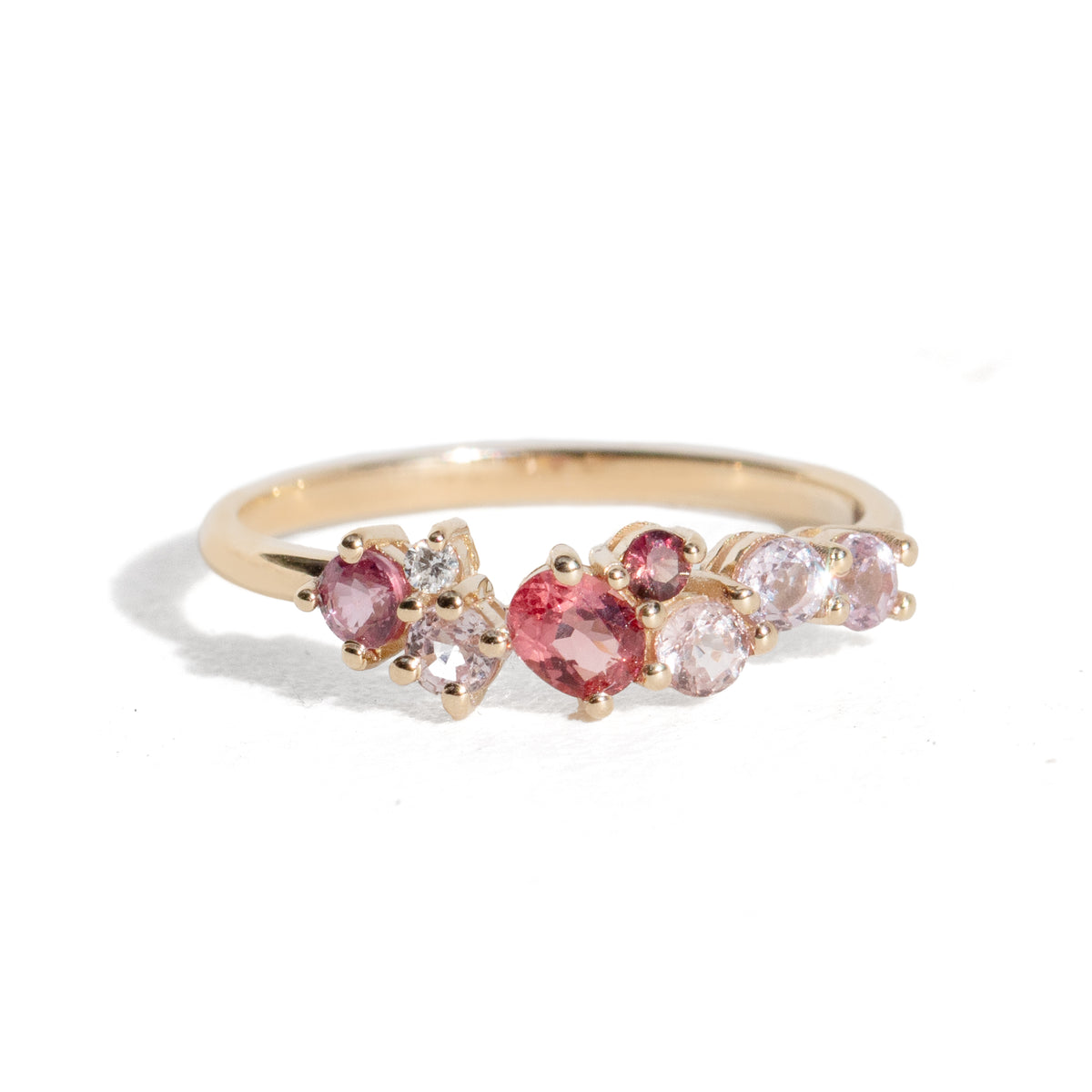 Gold ring with pink and red gemstones on a white background