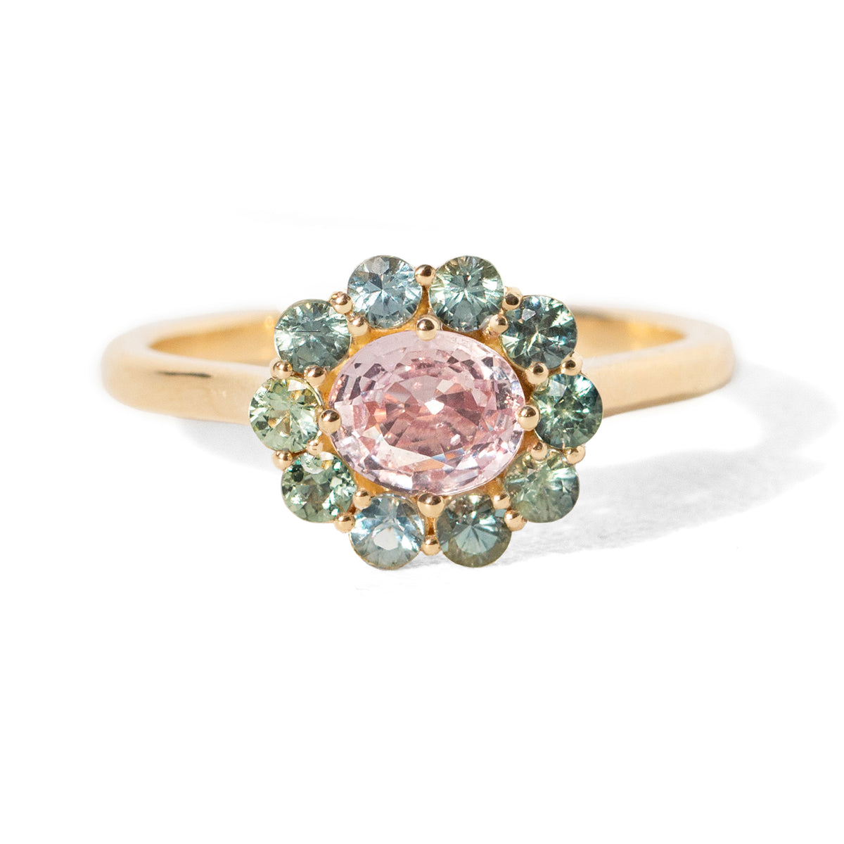 The 1.4 ctw. Pink Sapphire Charlotte Ring features a 3/4ct light pink sapphire at the center, framed by a variety of toned teal sapphires. The sweet and colorful halo design is truly one of a kind. This ring is perfect for those who appreciate timeless and unique designs. The slightly raised setting makes this ring fully stackable.