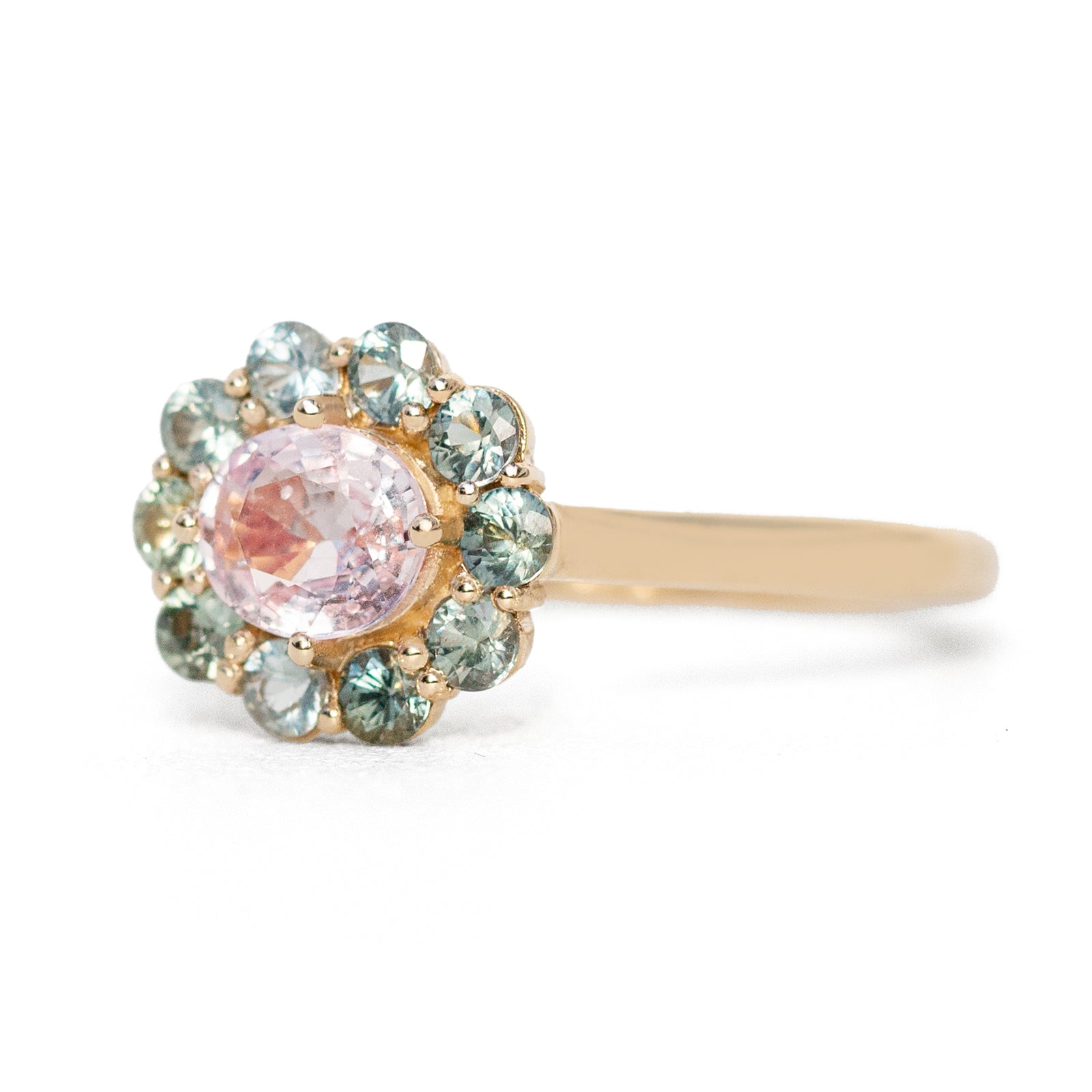 The 1.4 ctw. Pink Sapphire Charlotte Ring features a 3/4ct light pink sapphire at the center, framed by a variety of toned teal sapphires. The sweet and colorful halo design is truly one of a kind. This ring is perfect for those who appreciate timeless and unique designs. The slightly raised setting makes this ring fully stackable.