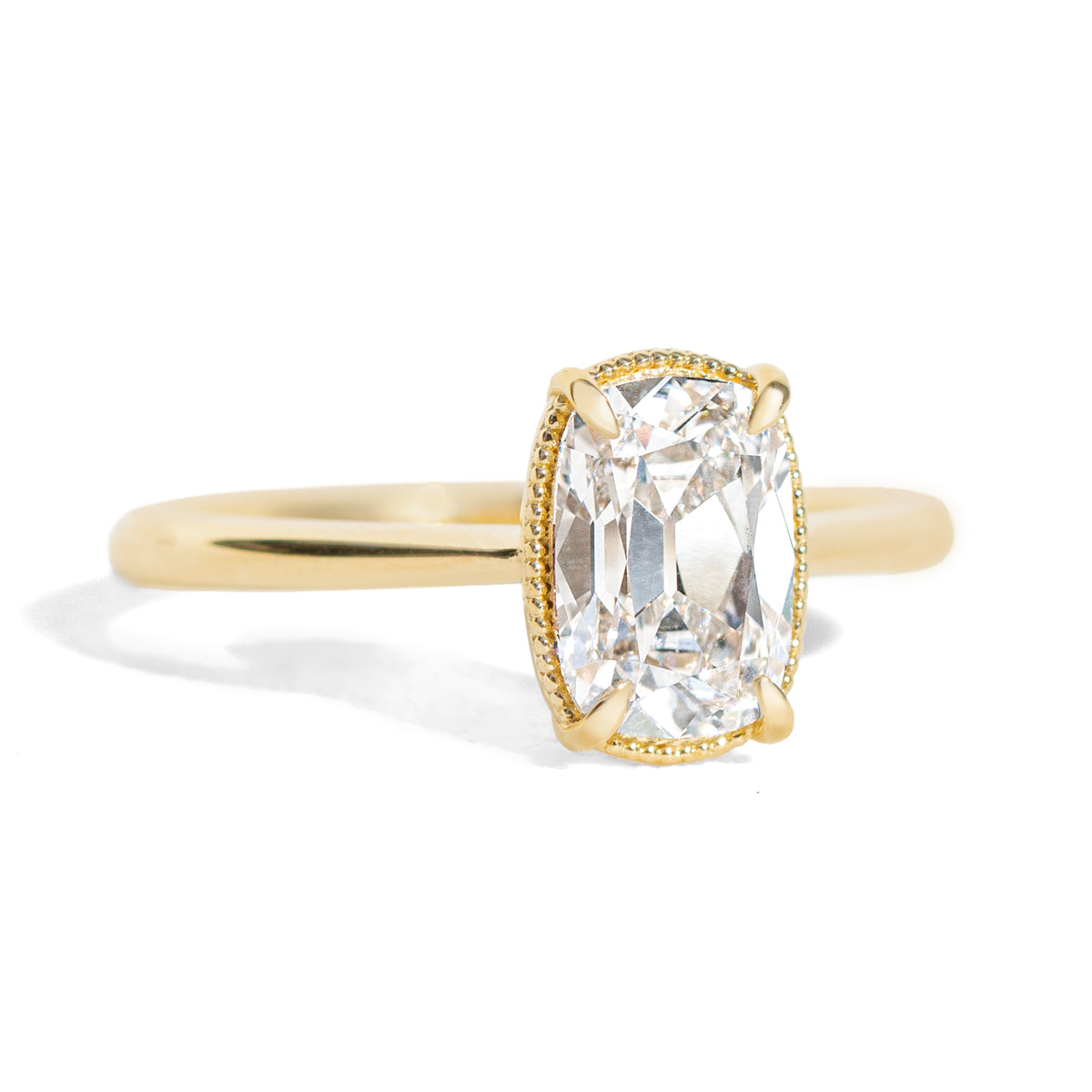 Gold milgrain ring with a 1.5 carat old mine cut diamond on a white background