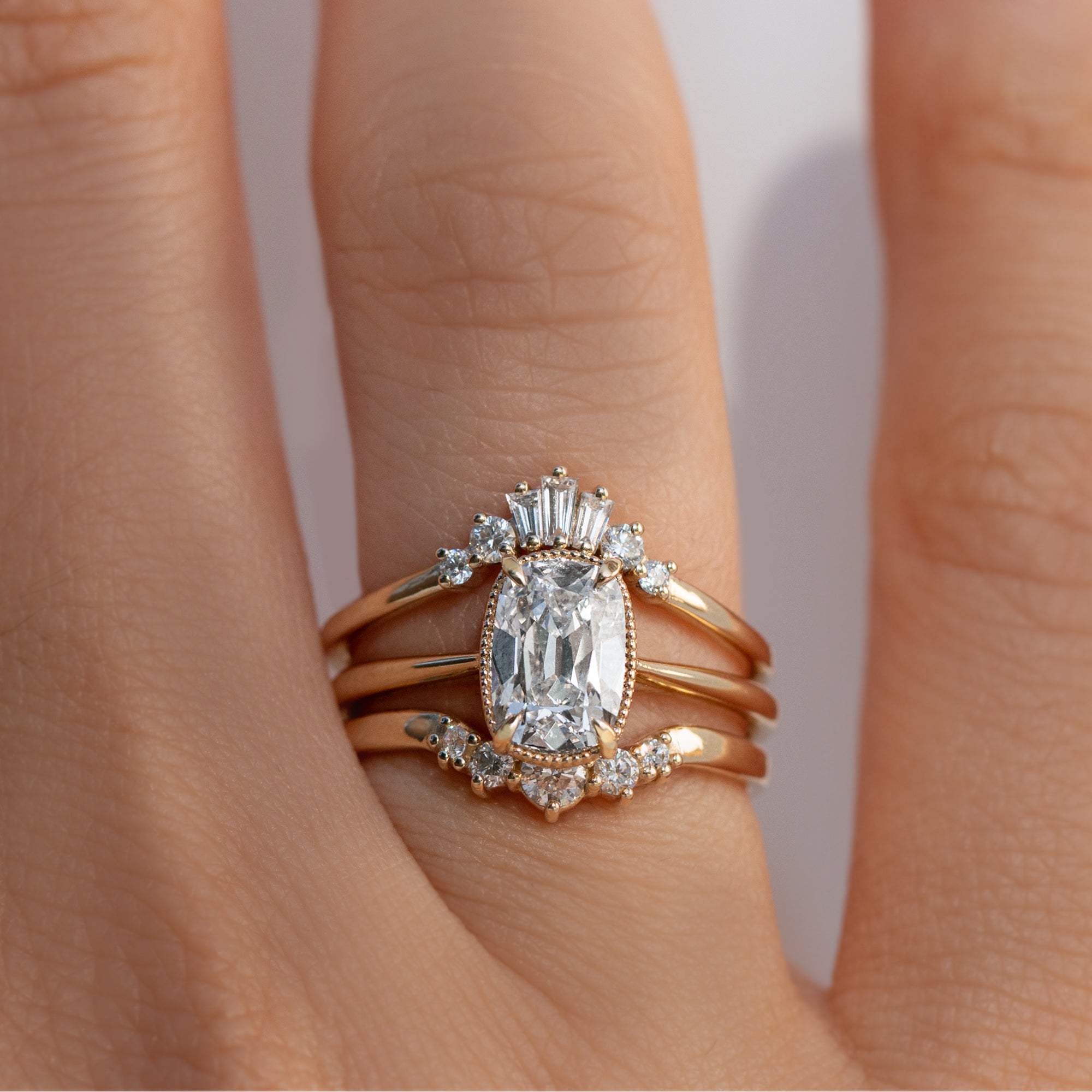 Gold milgrain ring with a 1.5 carat old mine cut diamond stacked with diamond bands on a hand 
