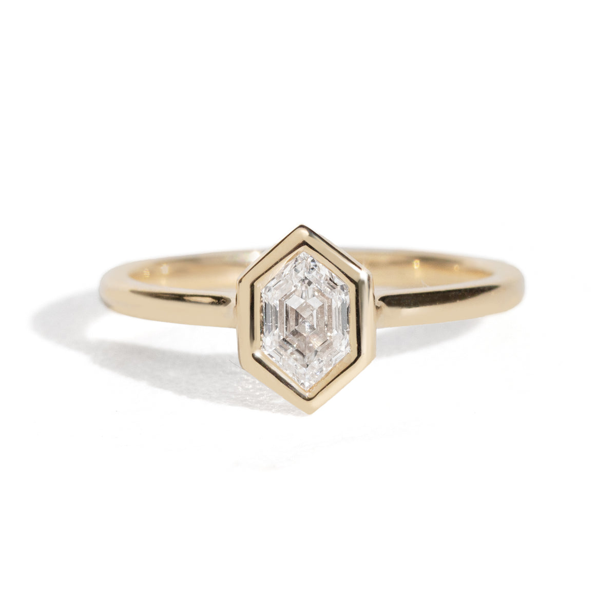 Gold ring with a diamond hexagonal stone on a white background