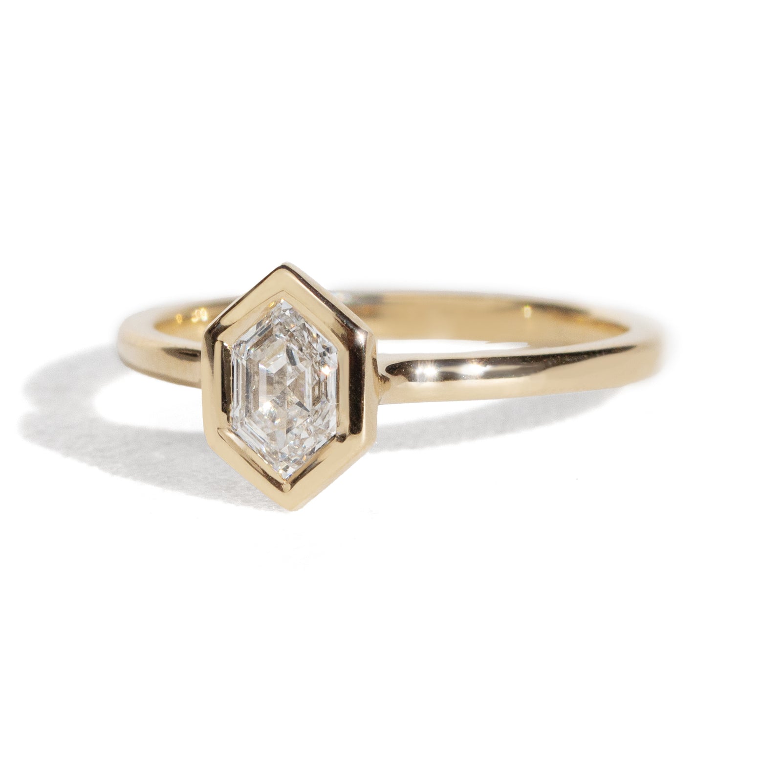 Gold ring with a diamond hexagonal stone on a white background