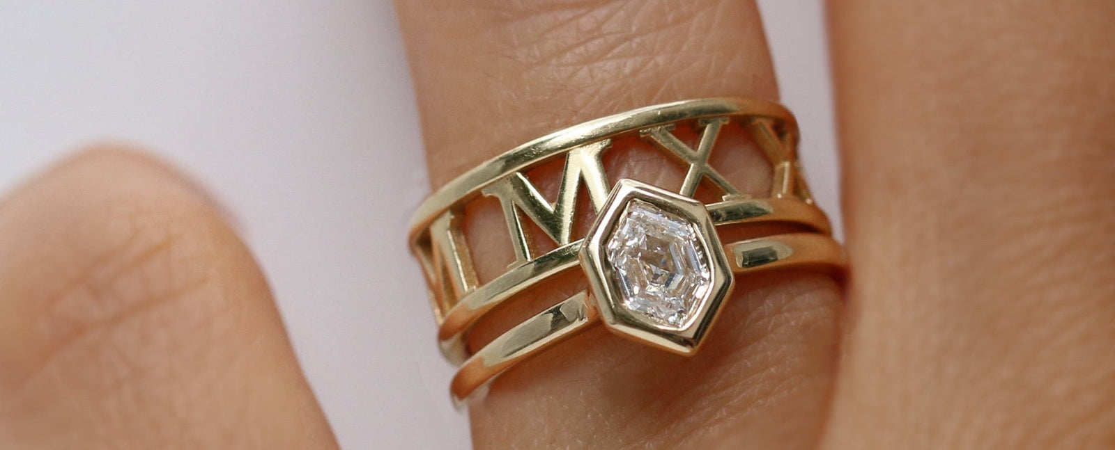 Gold ring with a diamond on a finger against a white background
