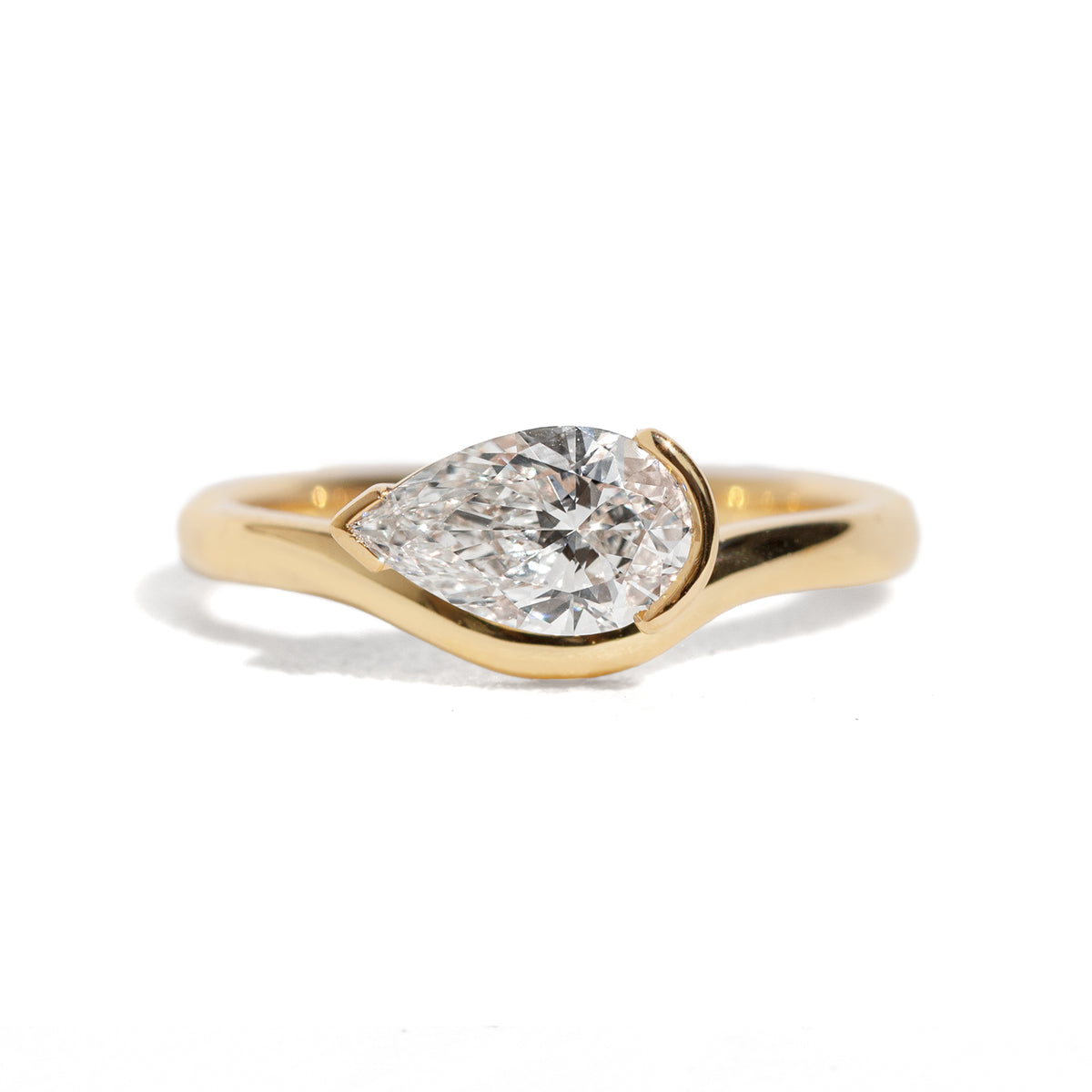 Gold ring with a pear-shaped diamond on a white background