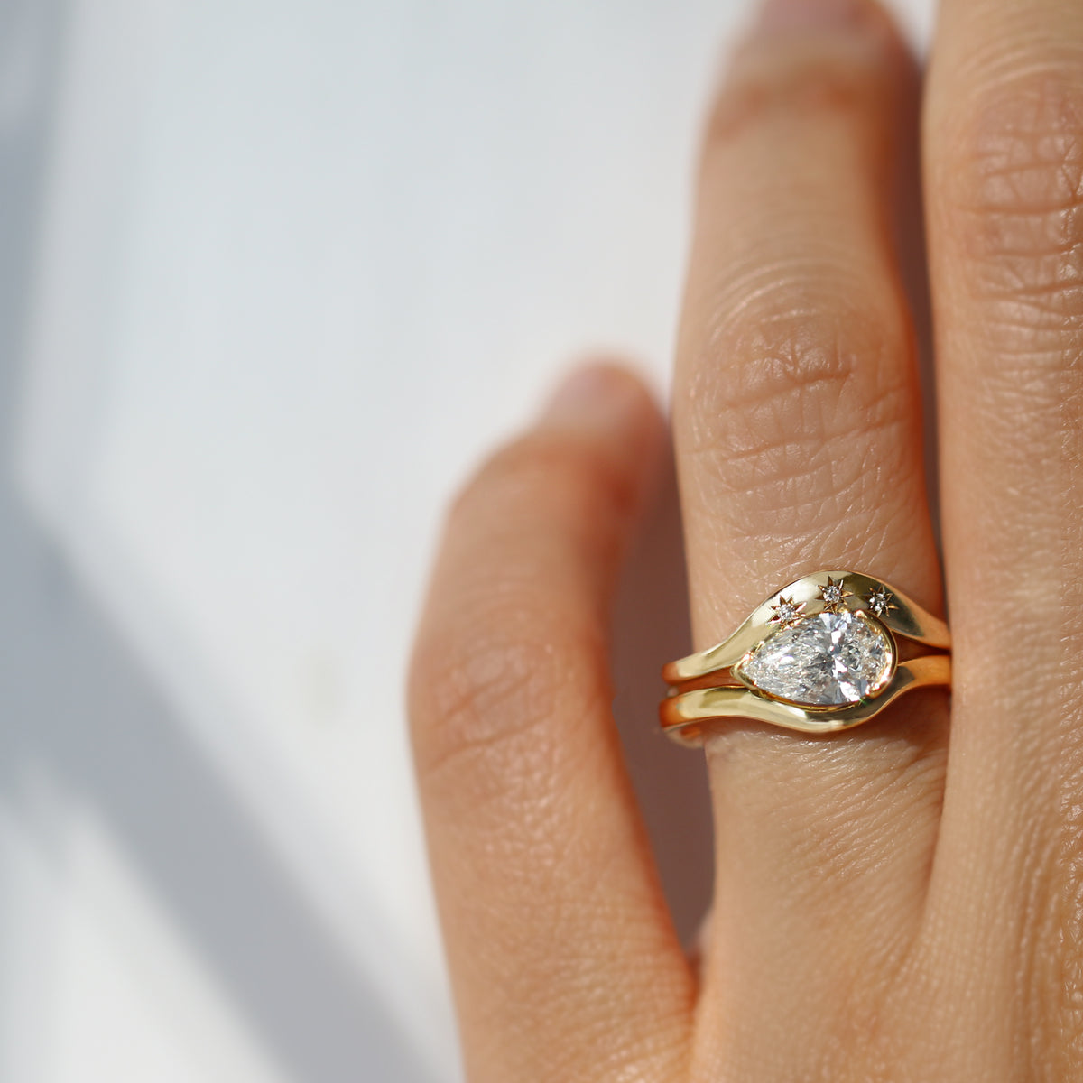 Gold ring with a diamond on a person&#39;s finger against a light background