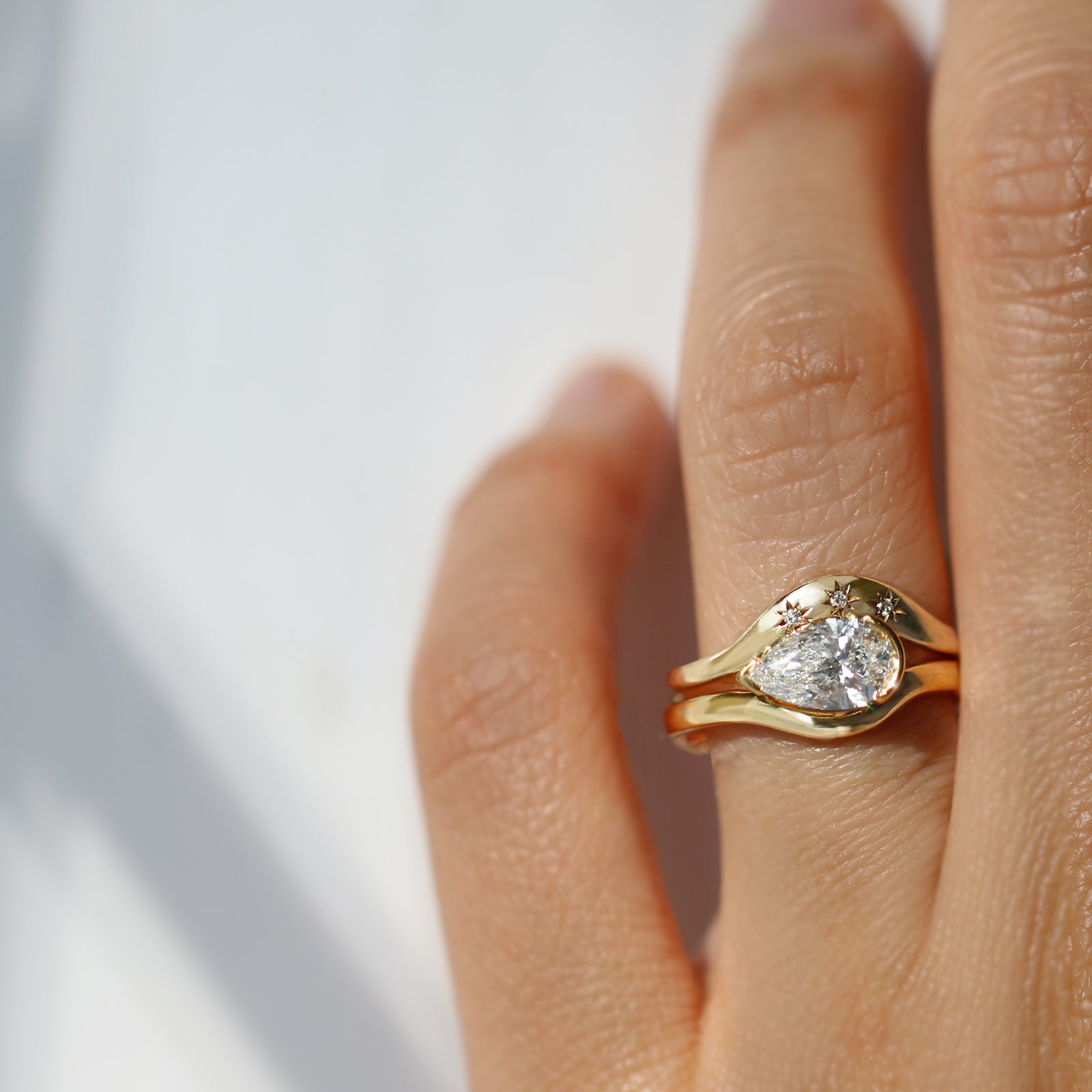 Gold ring with a diamond on a person's finger against a light background