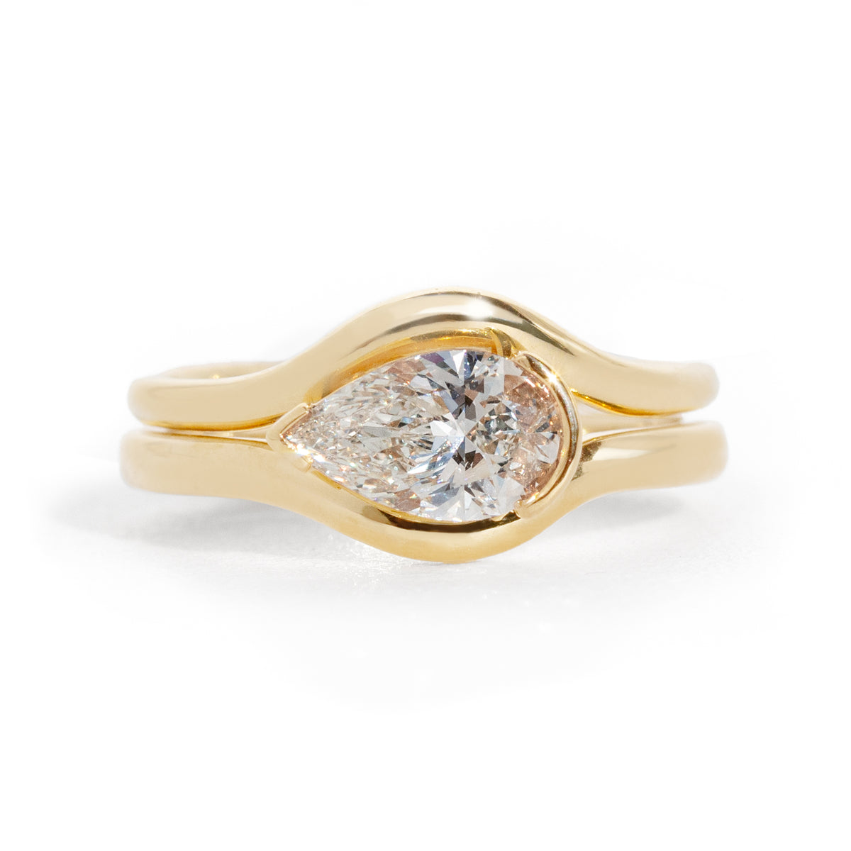 Gold ring with a pear-shaped diamond on a white background