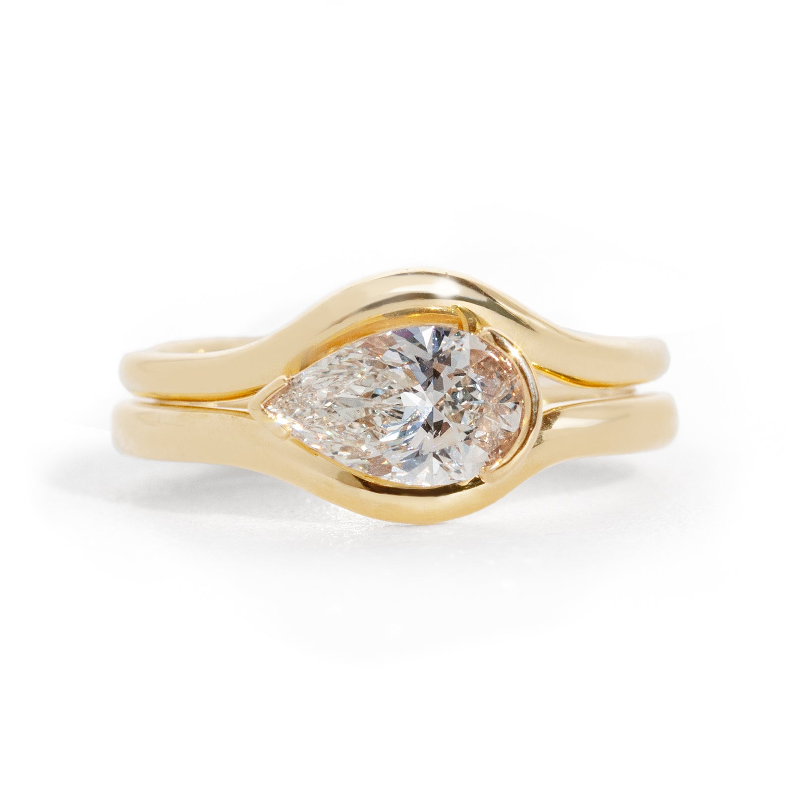 Gold ring with a pear-shaped diamond on a white background