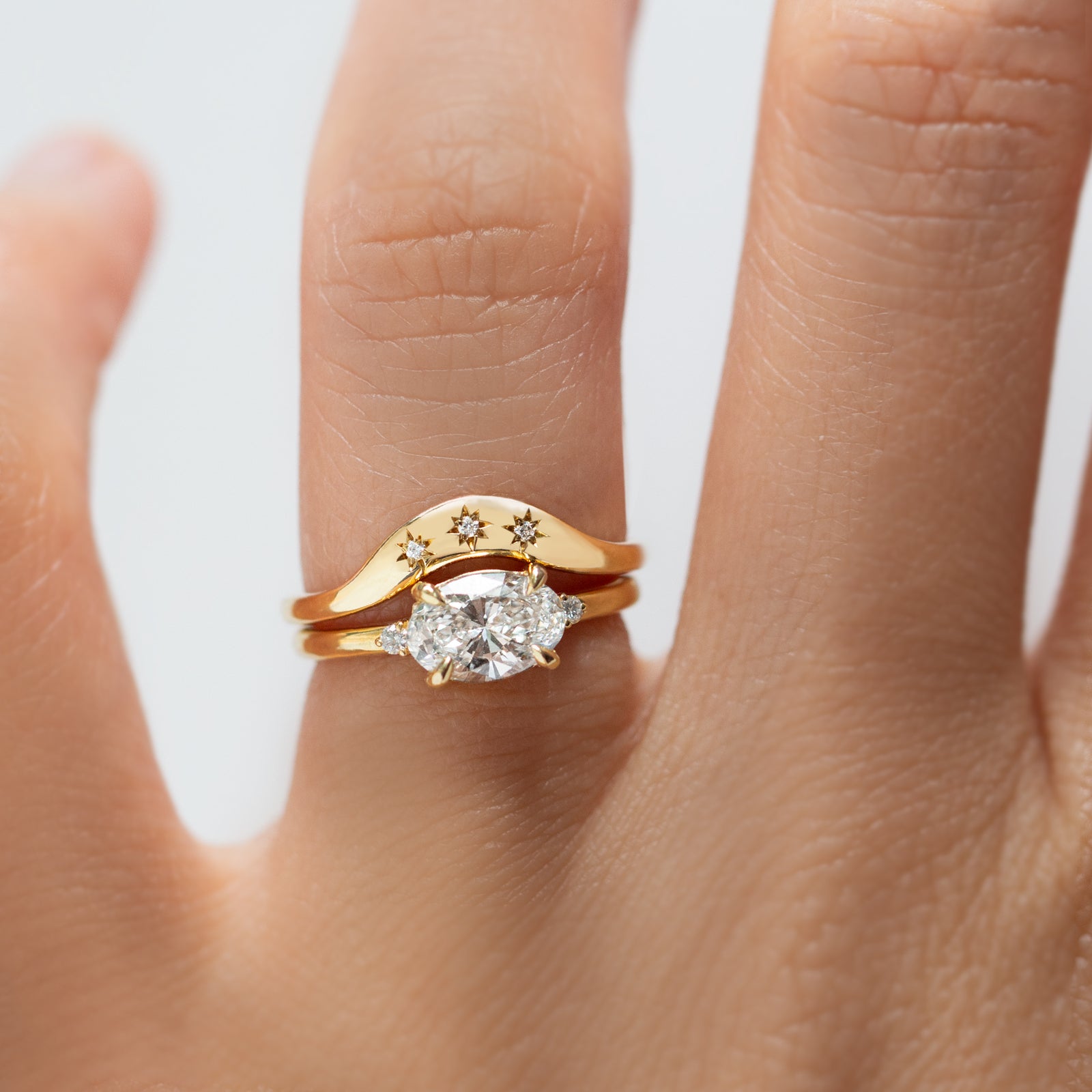Gold ring with a diamond on a person's finger against a light background