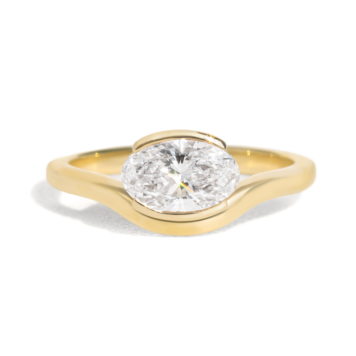 The Flow Ring features a 1 carat oval diamond or moissanite in a half bezel setting. The east west design adds a unique touch to this minimalistic design, making it the perfect subtle statement ring.
