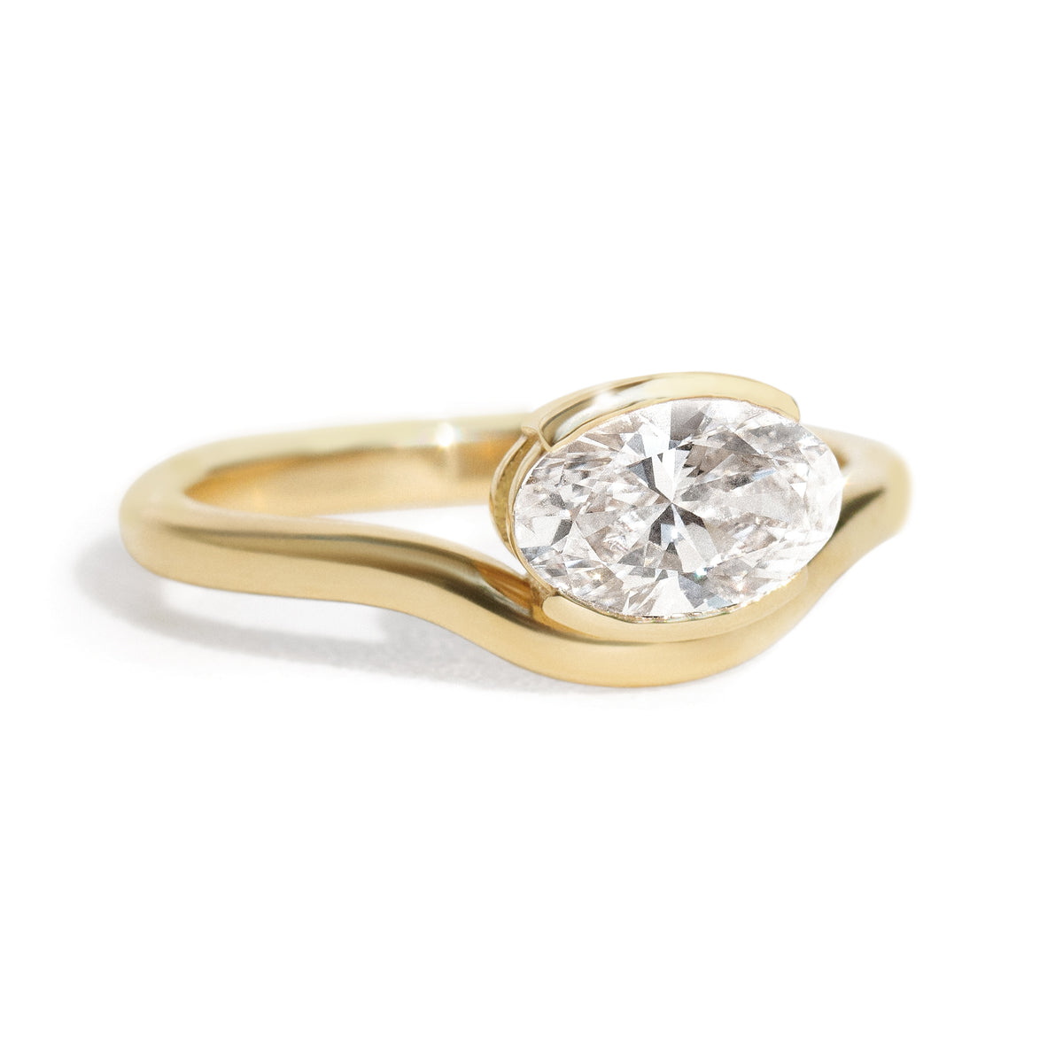 The Flow Ring features a 1 carat oval diamond or moissanite in a half bezel setting. The east west design adds a unique touch to this minimalistic design, making it the perfect subtle statement ring.