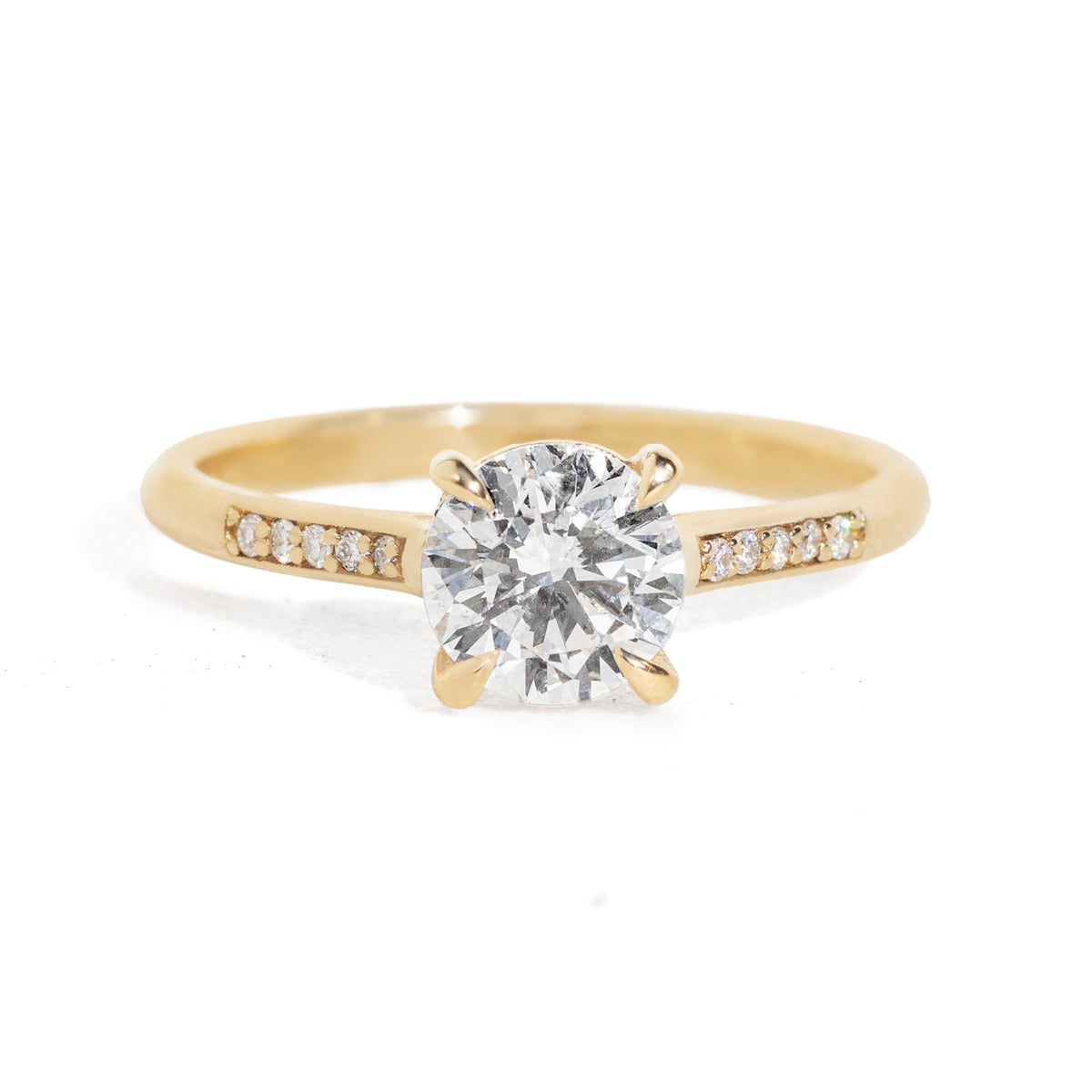 Gold ring with a large diamond and smaller diamonds on the band against a white background