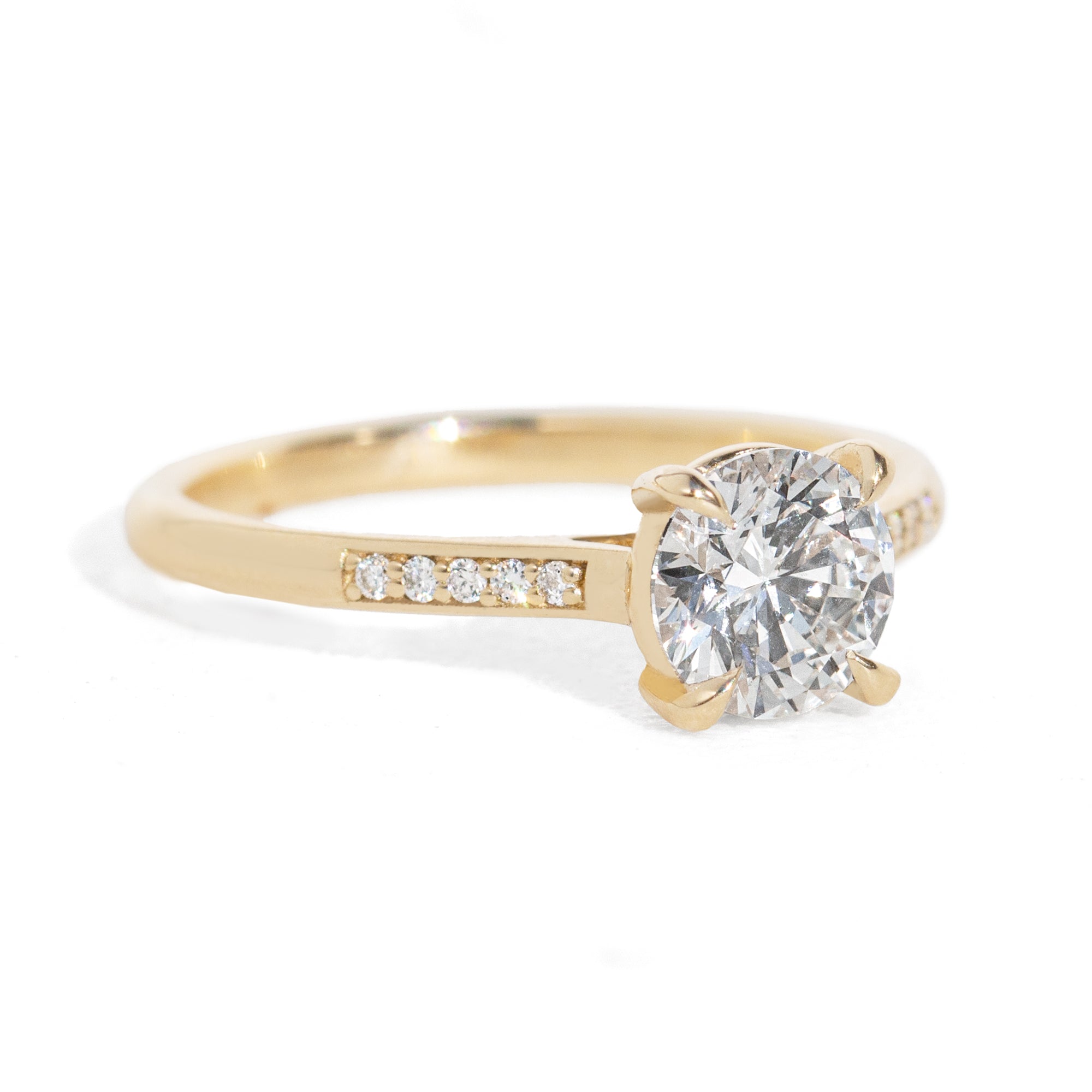 Gold ring with a large diamond and smaller diamonds on the band against a white background
